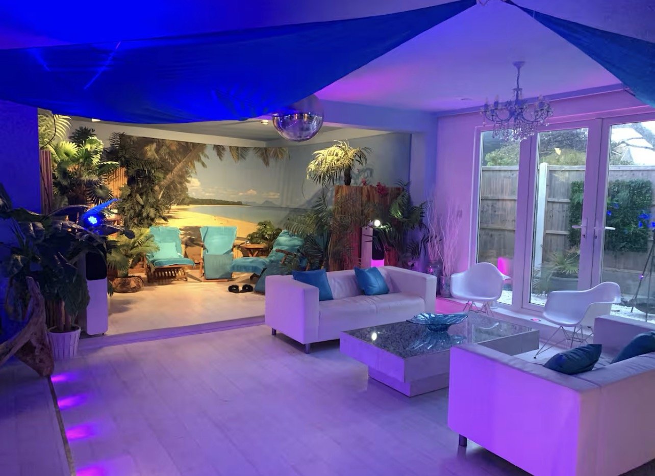 A purple-lit lounge in the evening with a tropical beach mural