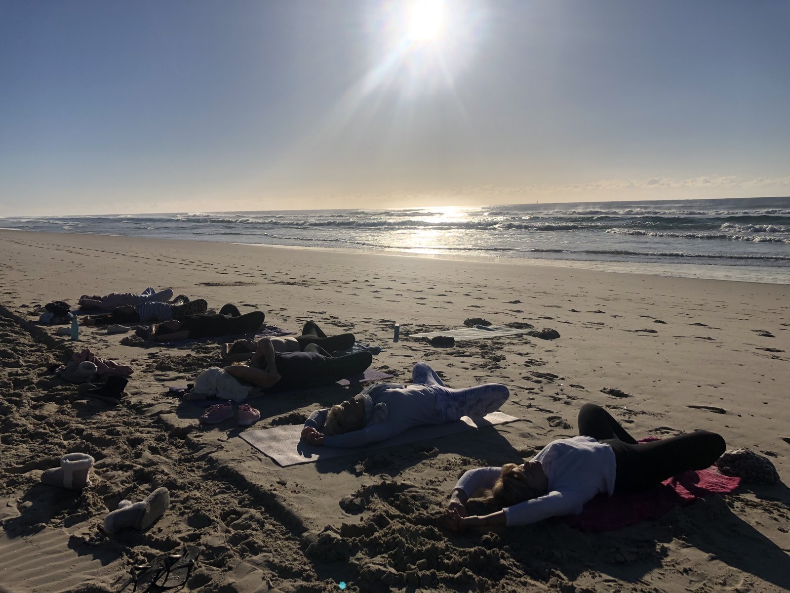 A group of women resting together on the beach at sunrise