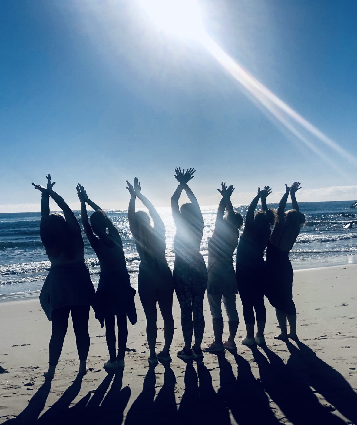 Silhouettes of women with arms raised on the beach