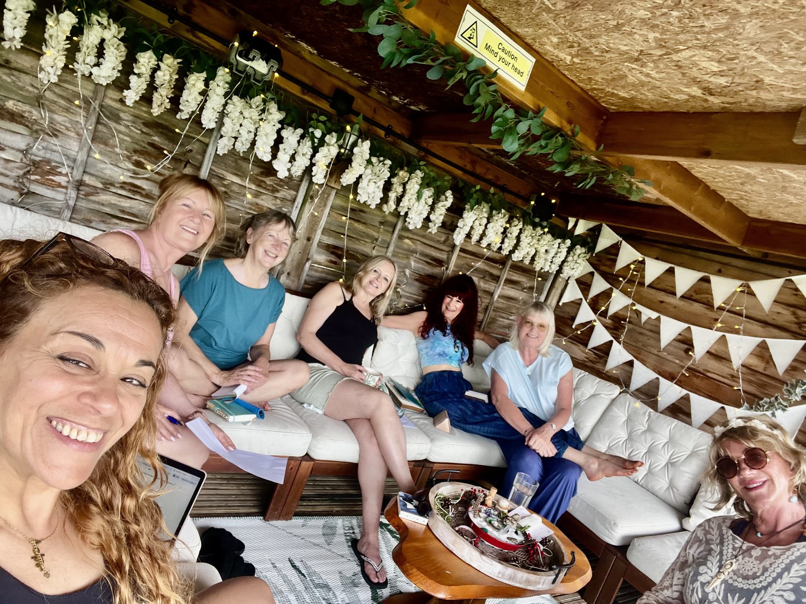 A joyful group of women together in a flower-strung cabana with fairy lights