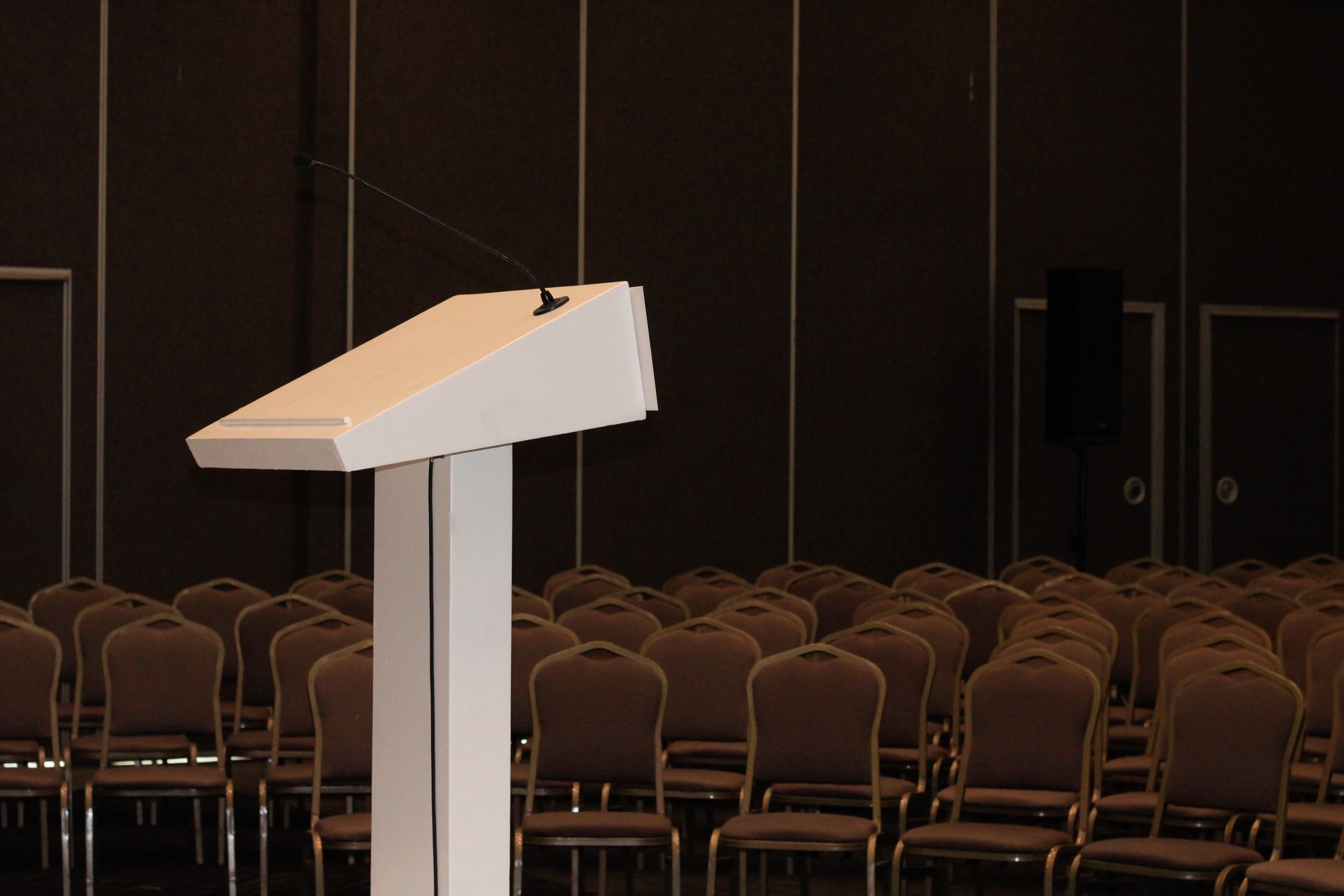 An empty conference room setup with podium and rows of chairs