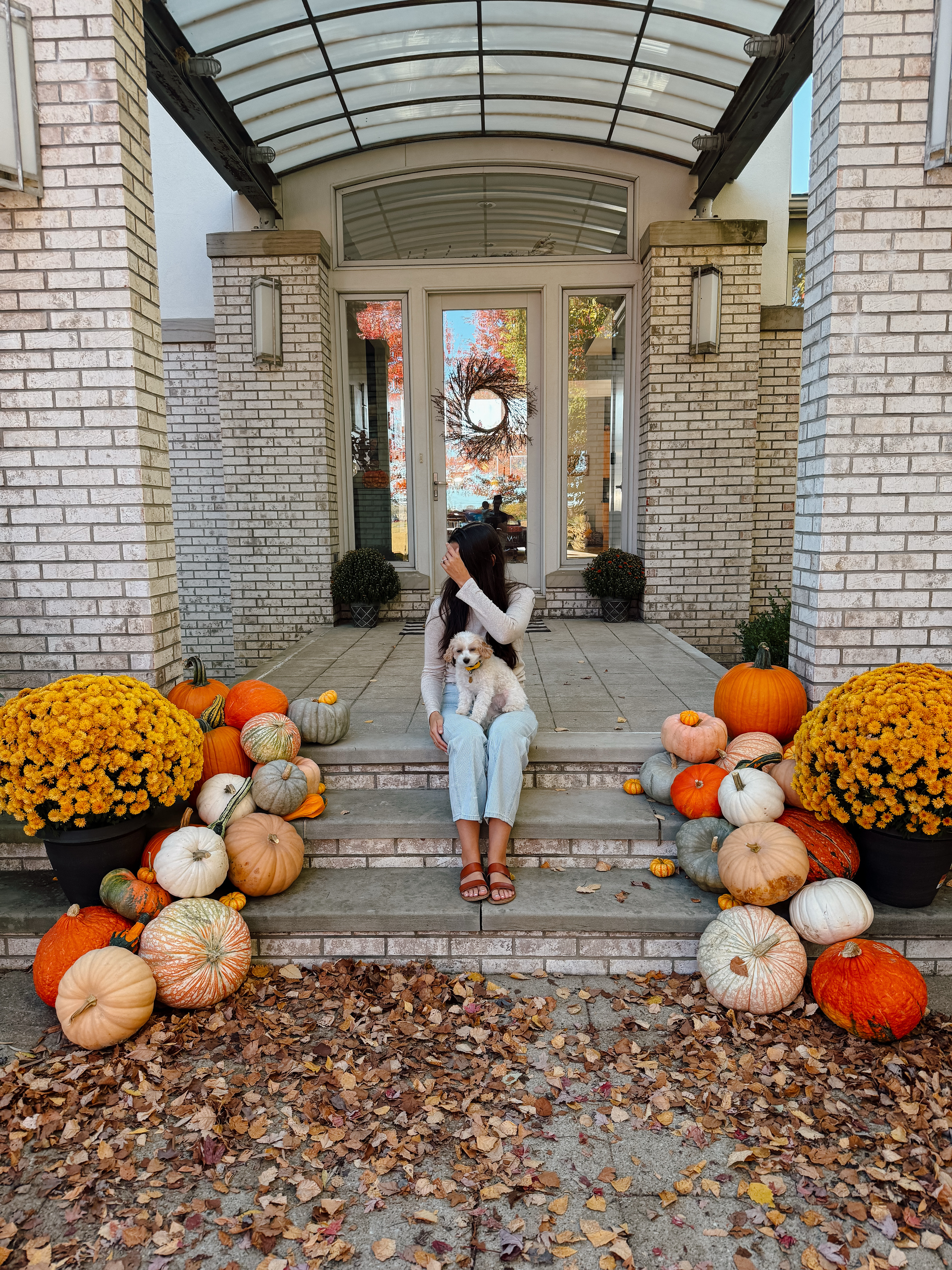 A grand stone entryway styled with pumpkins, gourds, and mums by The Local Pumpkin in Geauga County, Ohio