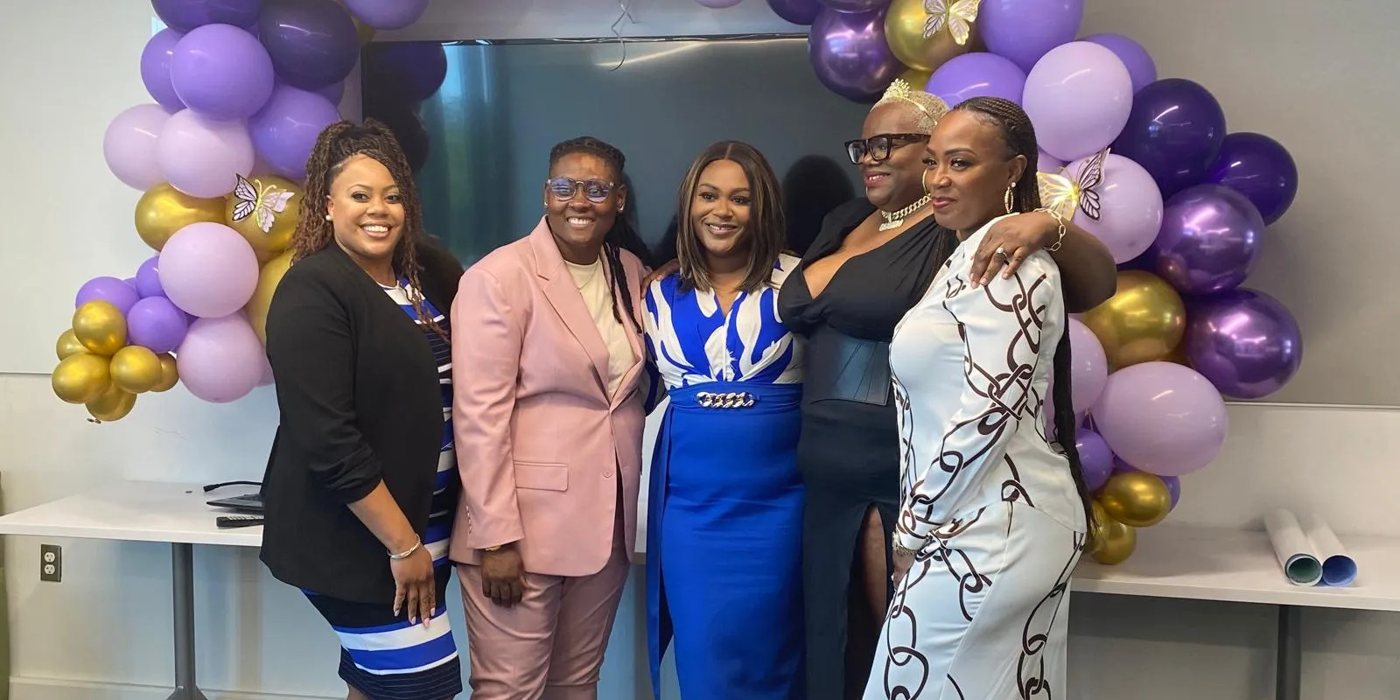 InspireHer women celebrating under purple and gold balloons