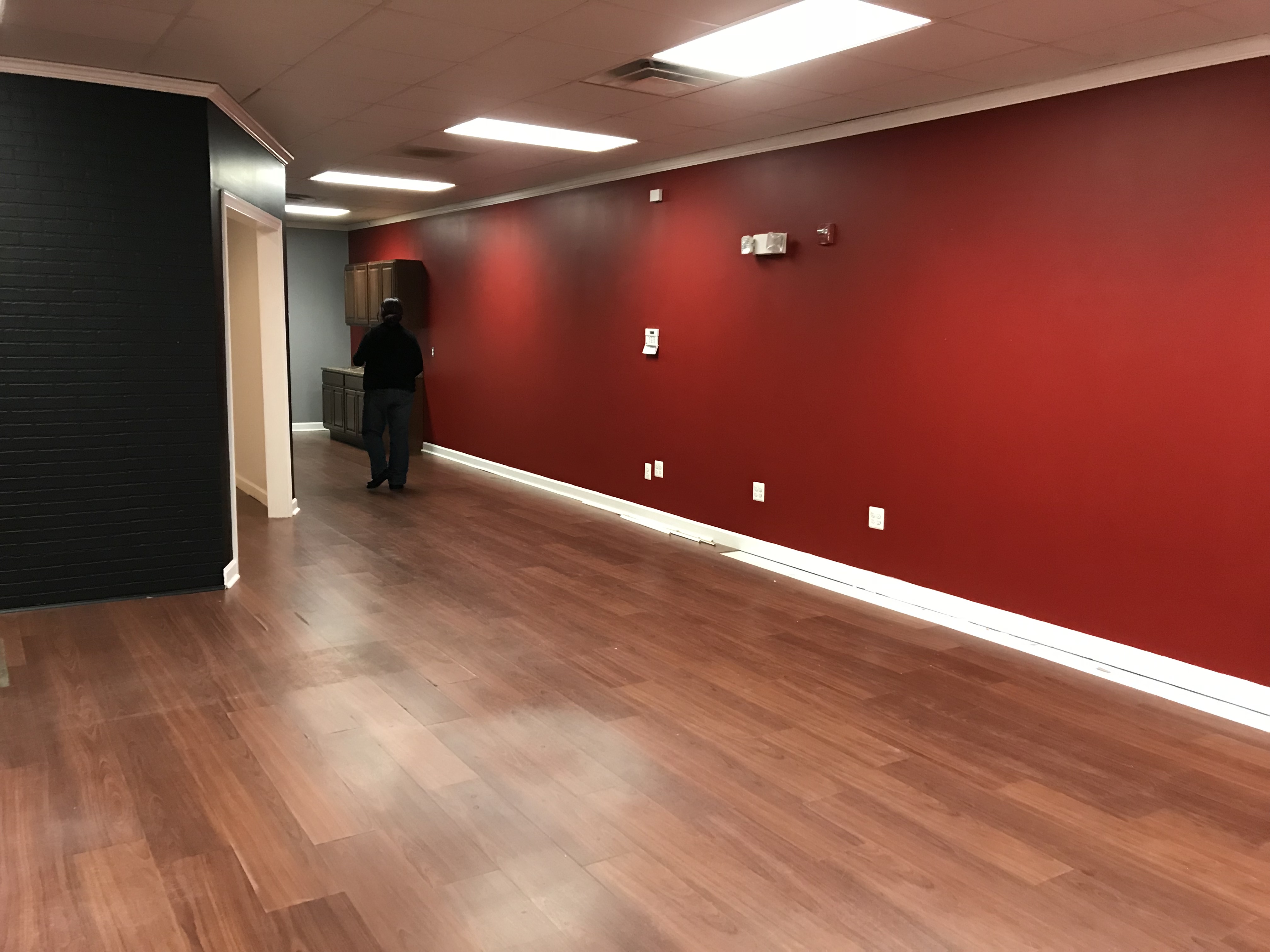 Before renovation: open commercial space with a bold red wall