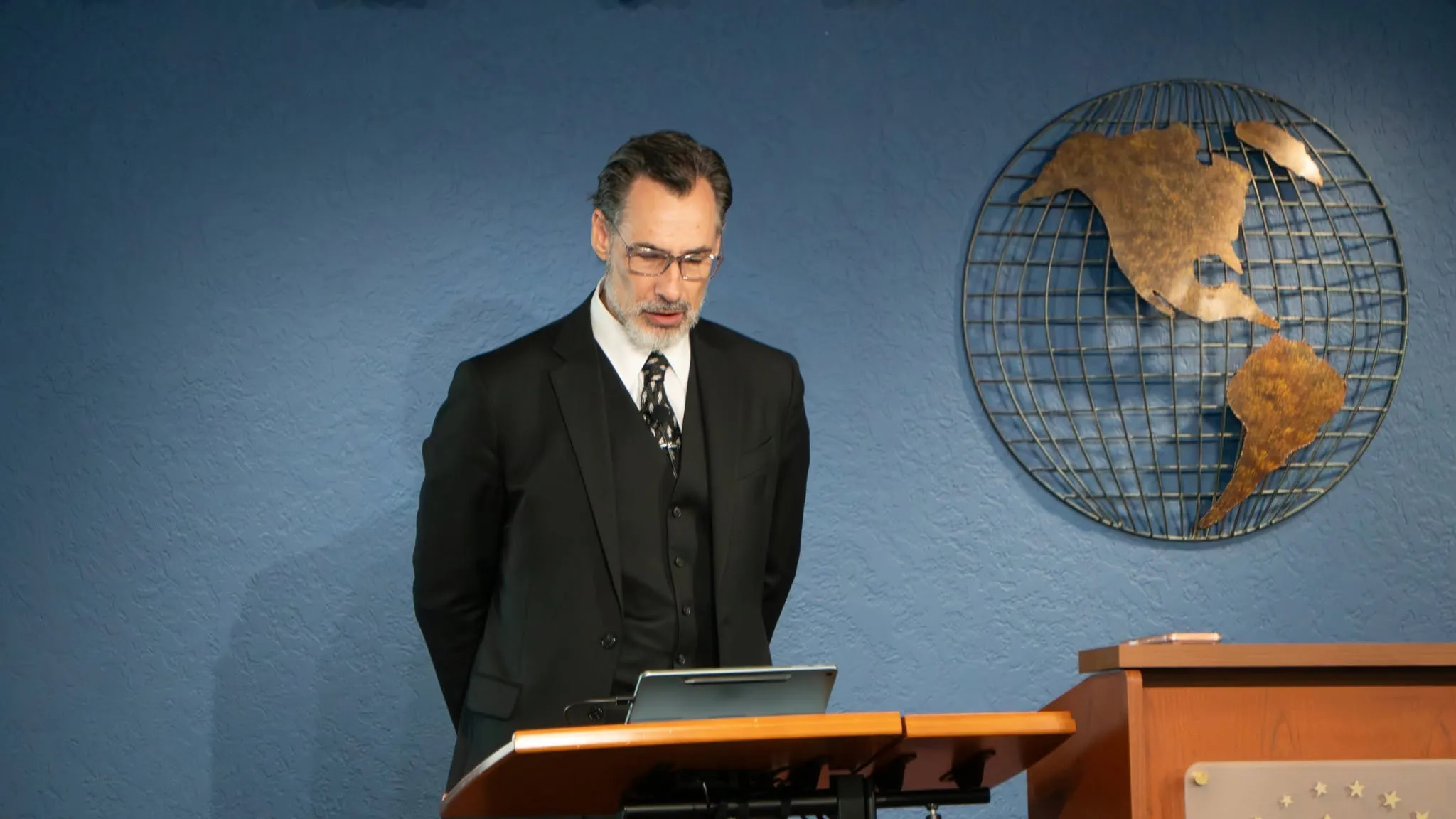 A presenter in a three-piece suit speaking from the lectern at a Smile Care Claims seminar