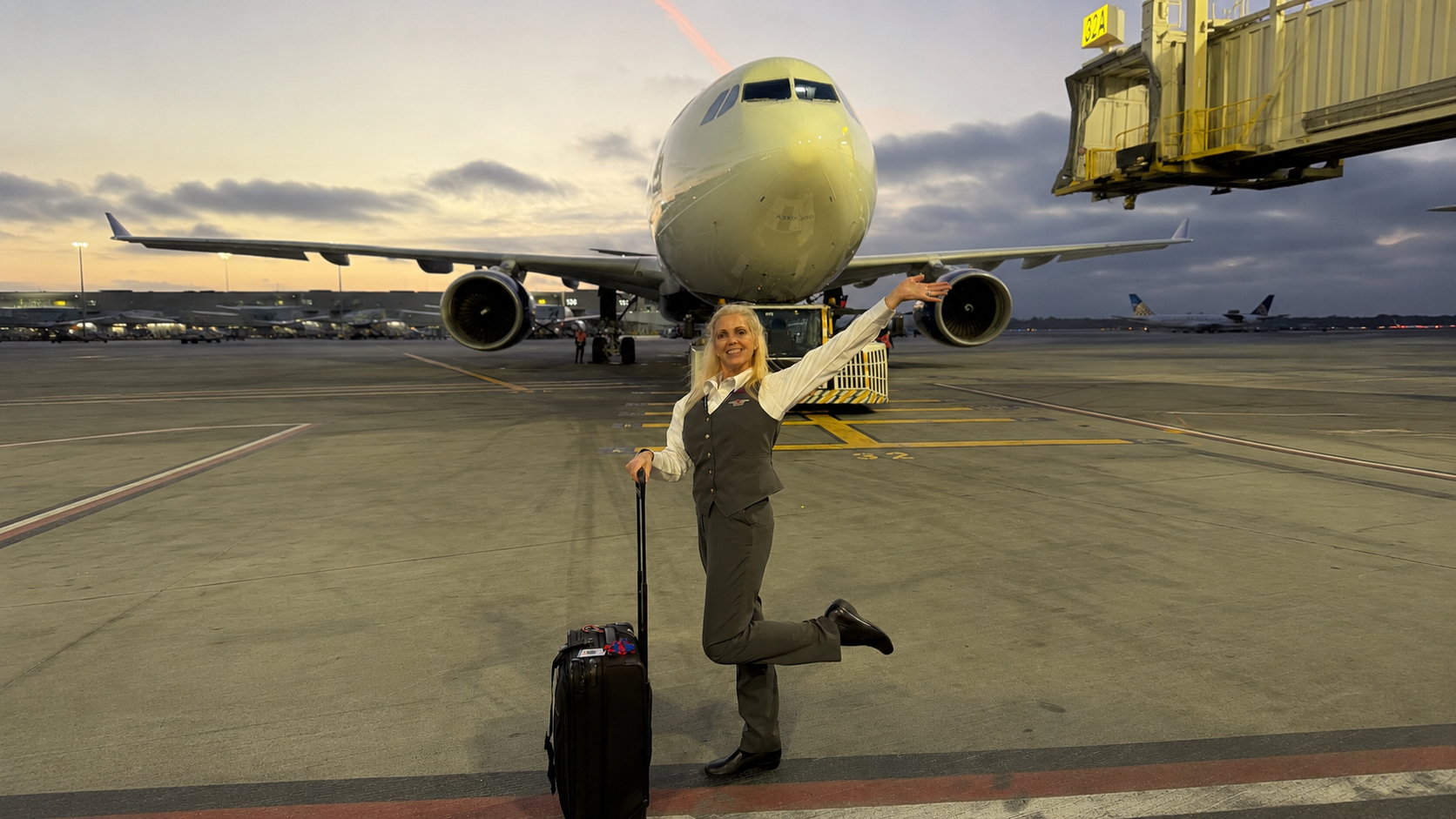 Elizabeth Garrison in flight attendant uniform standing with her suitcase in front of an aircraft after changing careers in midlife. Elizabeth Garrison in flight attendant uniform standing with her suitcase in front of an aircraft after changing careers in midlife.