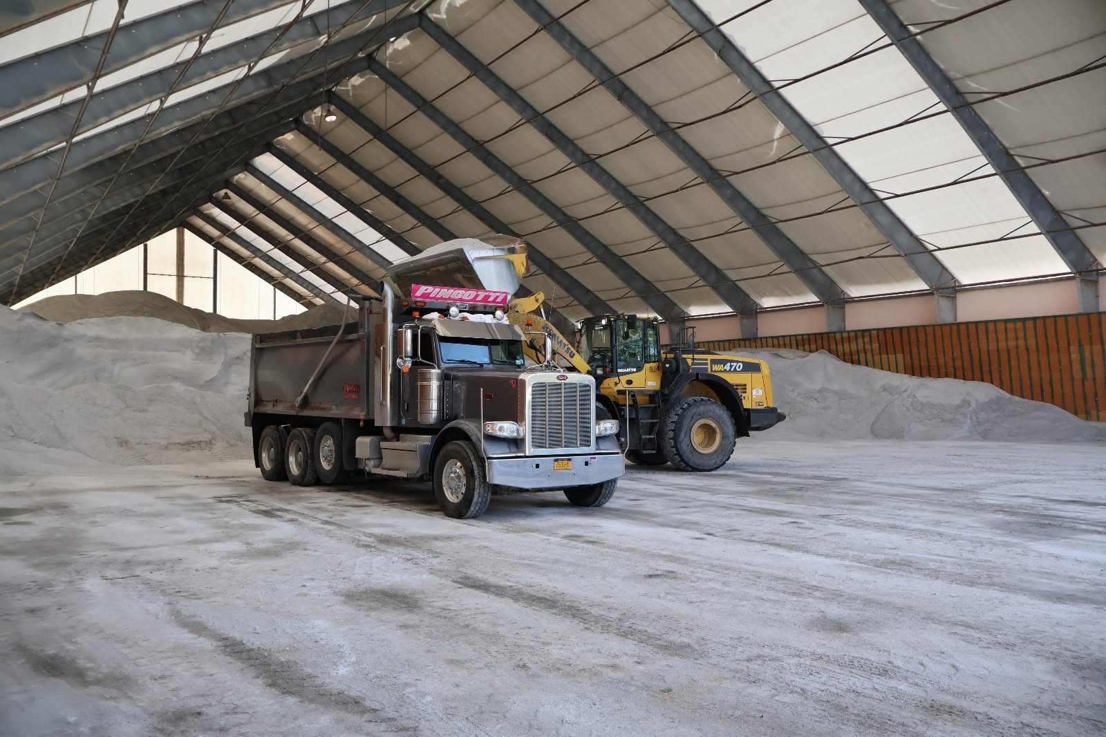 Dump truck and loader inside a salt storage building