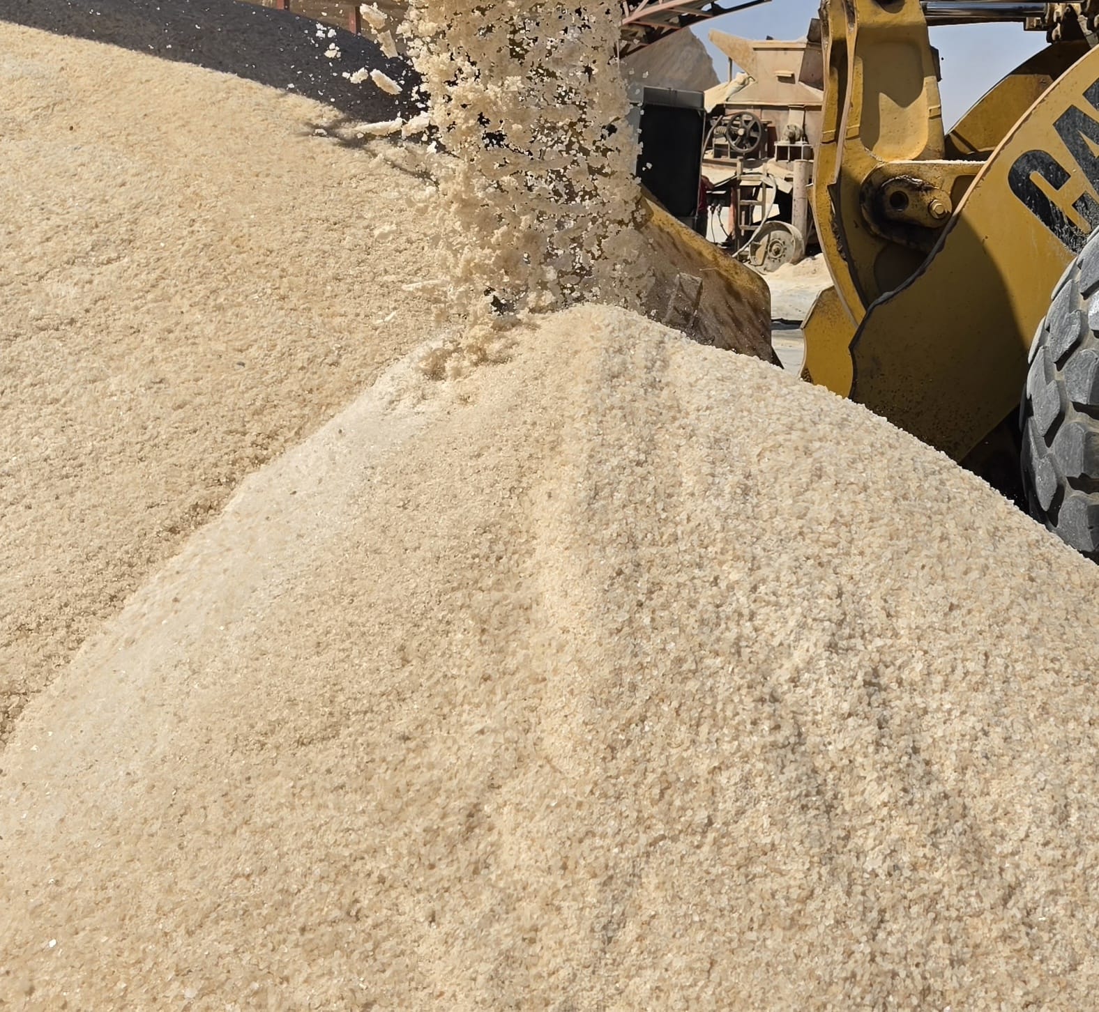 Loader pouring golden rock salt onto a pile