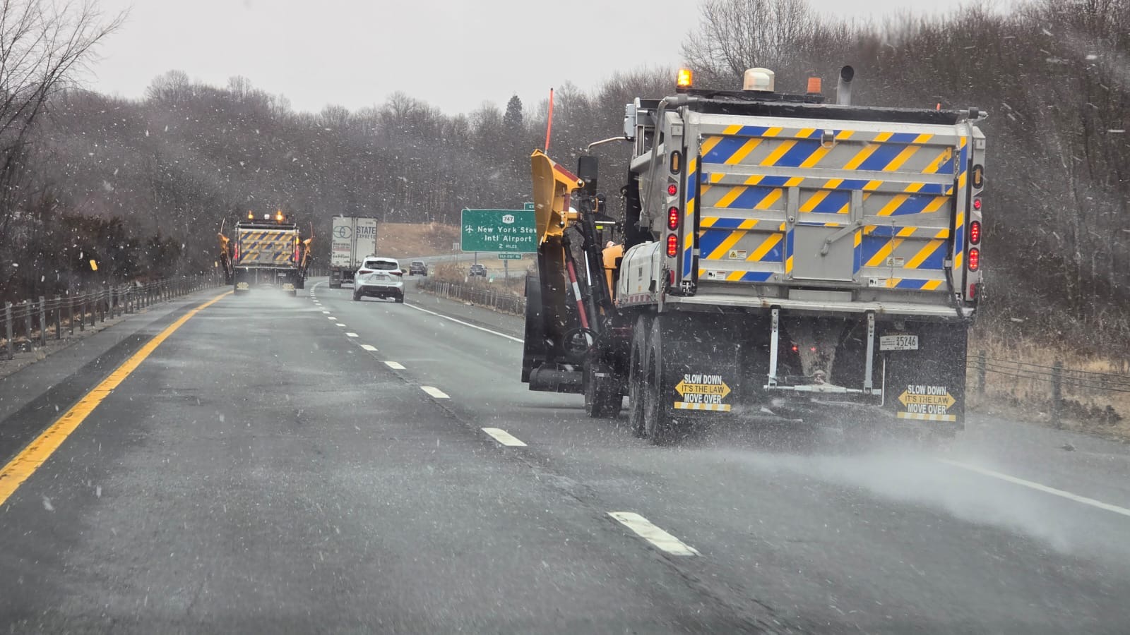 Spreader truck treating a highway in snow