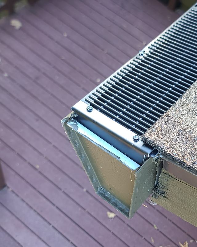 Gutter end cap with the Raindrop guard fastened down, above a deck