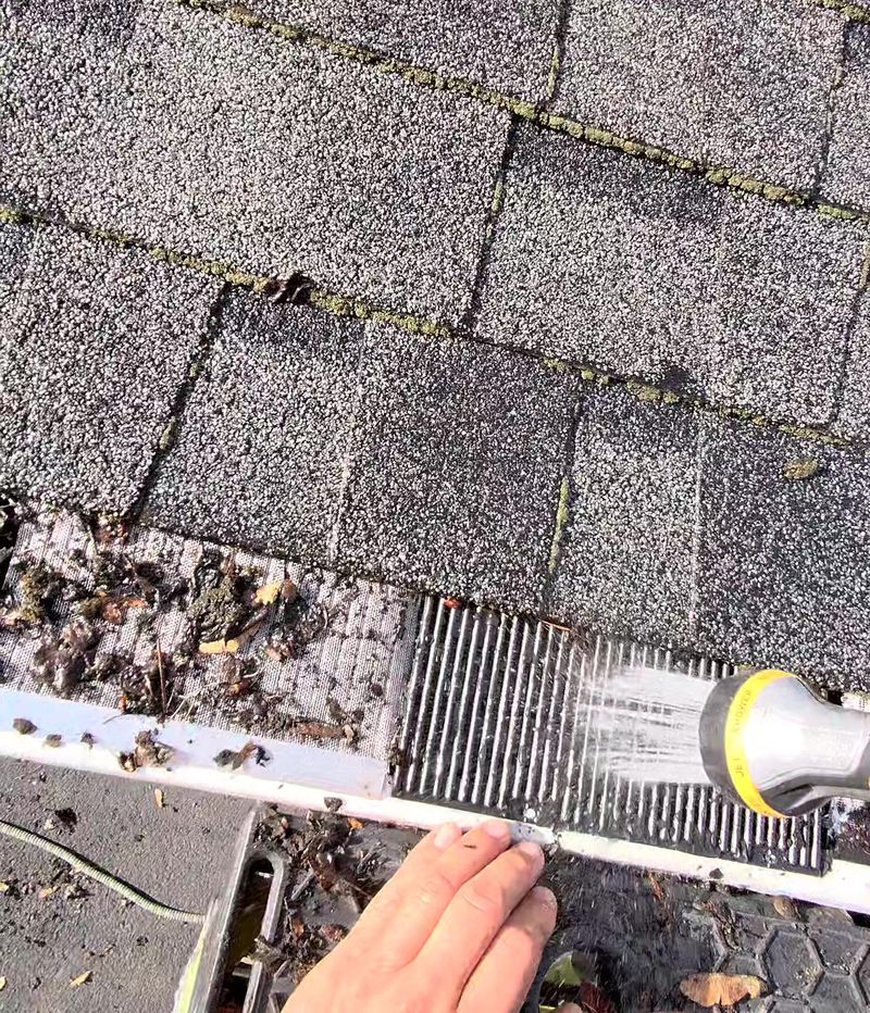 Hose spraying water onto Raindrop and other gutter guard samples on a roof