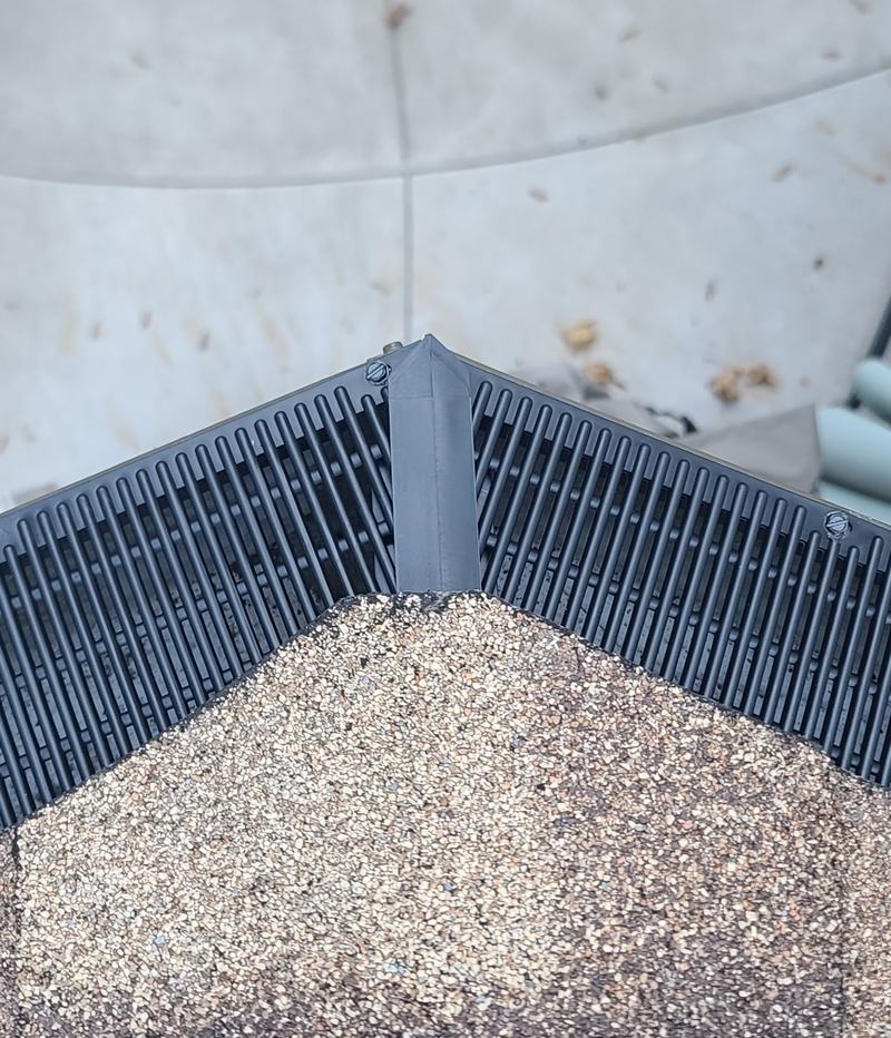 Close-up of a Raindrop gutter guard miter with a corner cap, the open grid visible on both runs