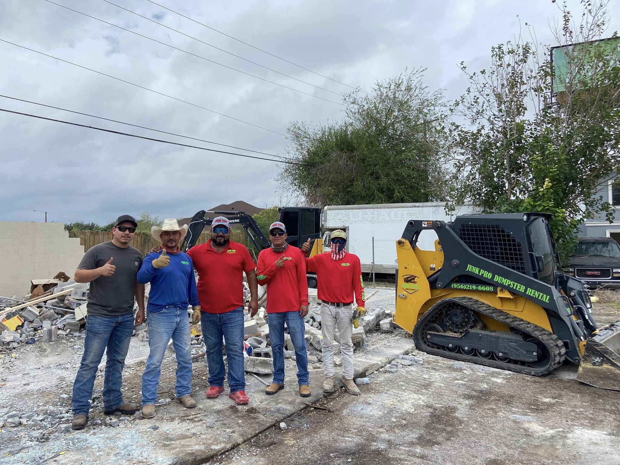JunkPro CEO Victor standing with the team in front of heavy demolition equipment in the Rio Grande Valley