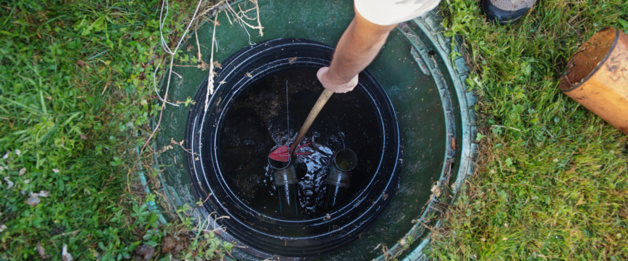 Worker inspecting and maintaining an underground septic tank system