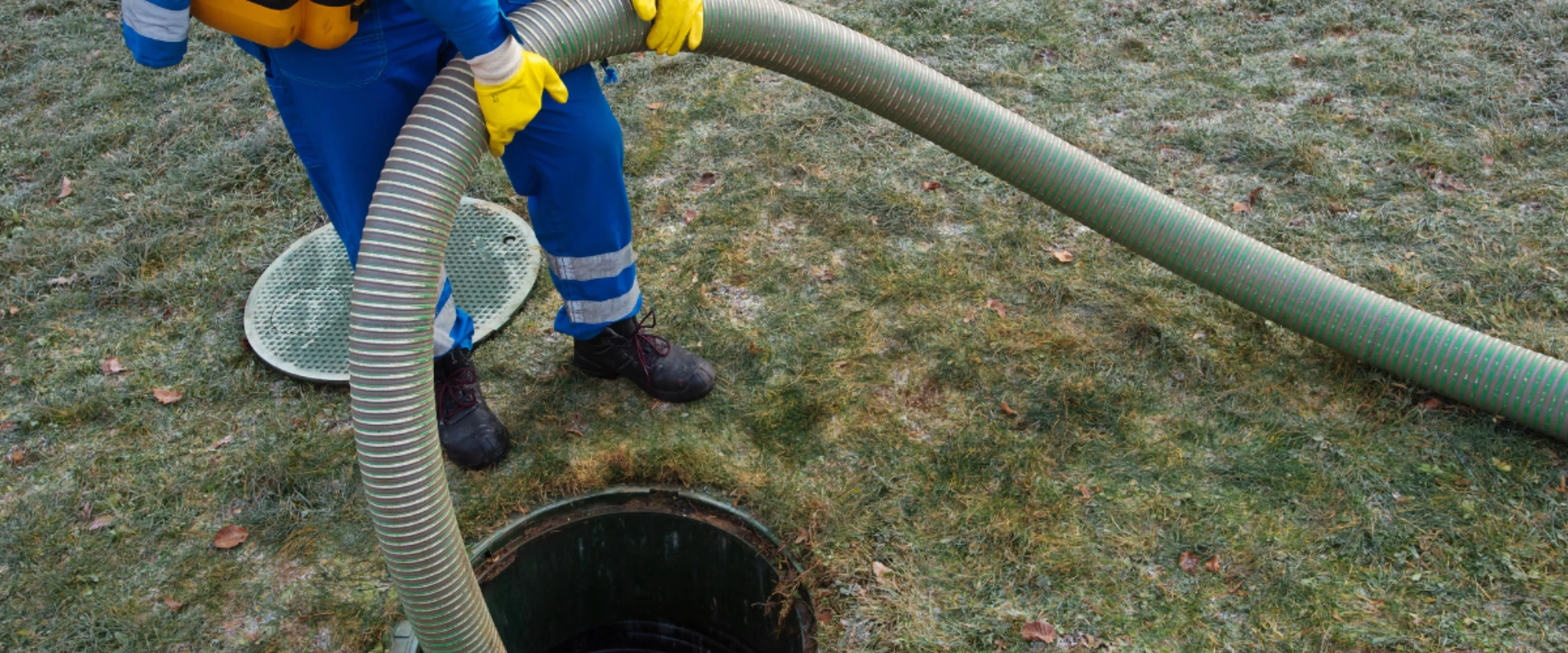 Technician using a large hose to pump and empty a septic tank