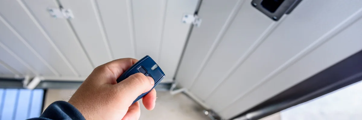 Hand holding remote control to open automatic garage door.