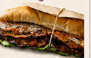 A b&aacute;nh m&igrave; sandwich on a crisp baguette with grilled meat and vegetables