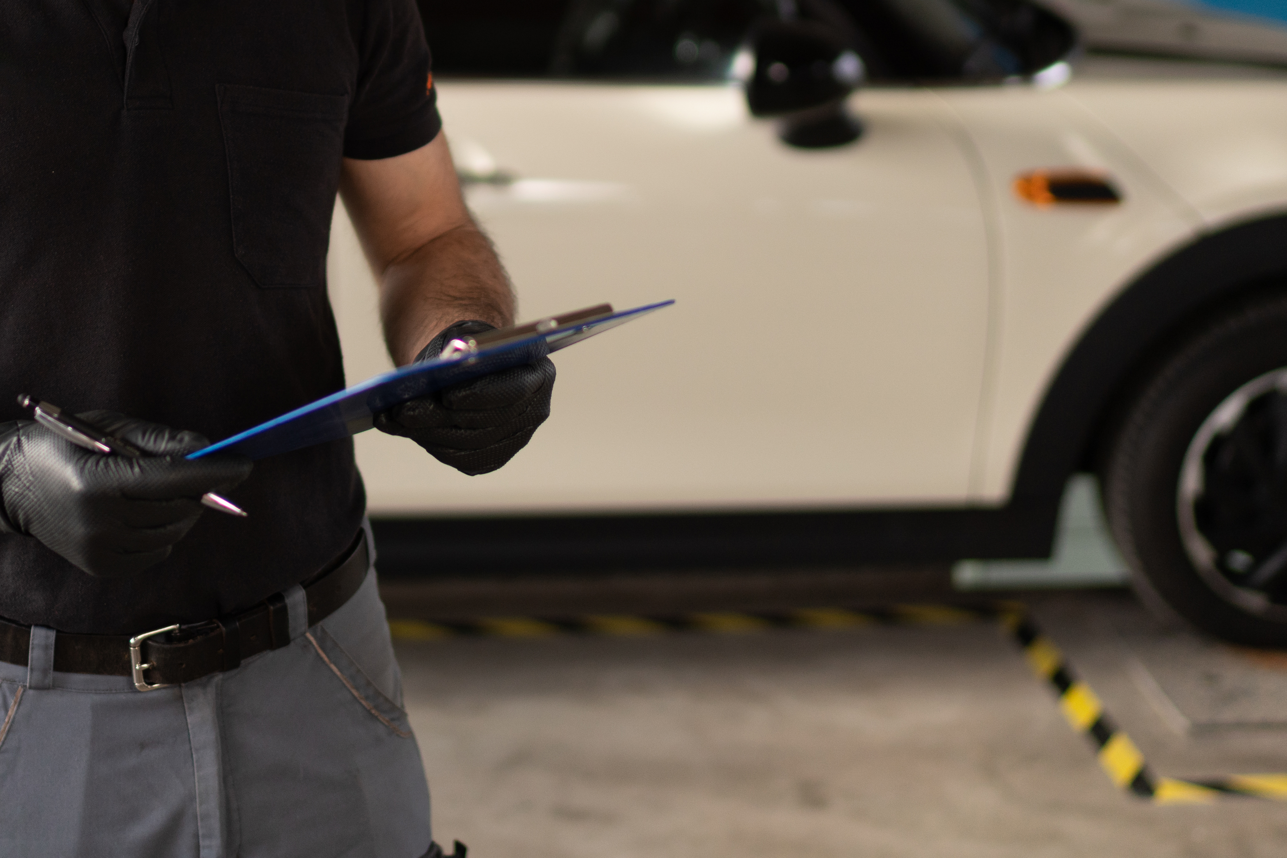 Mechaniker bei einer Fahrzeuginspektion in der Werkstatt, Motorraum geöffnet und geprüft