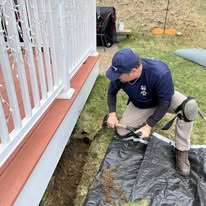 Technician installing ground exclusion along a foundation