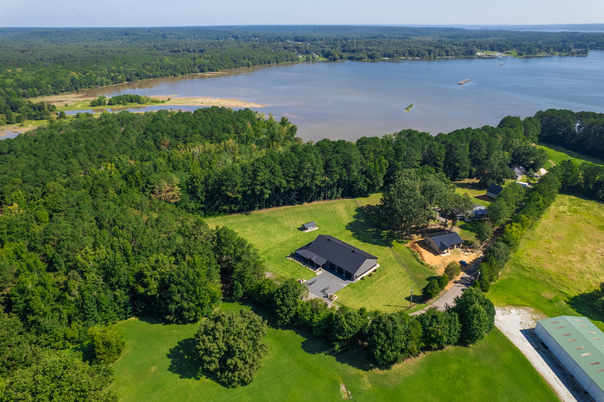 Aerial view of a home surrounded by green acreage near a lake