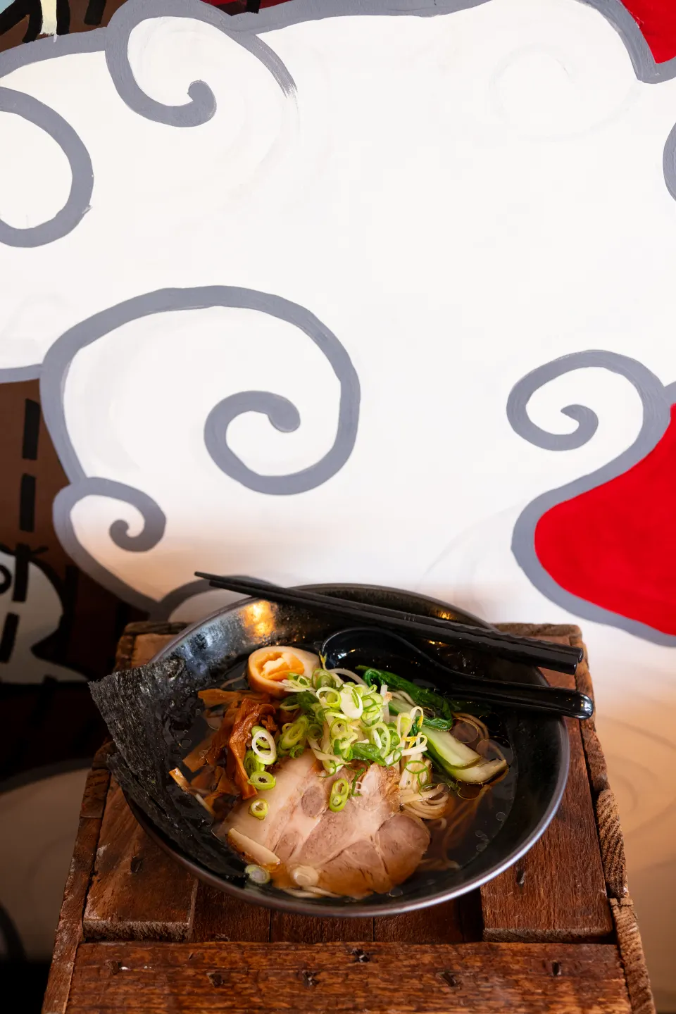Close-up of a Pompoko ramen bowl on a timber crate