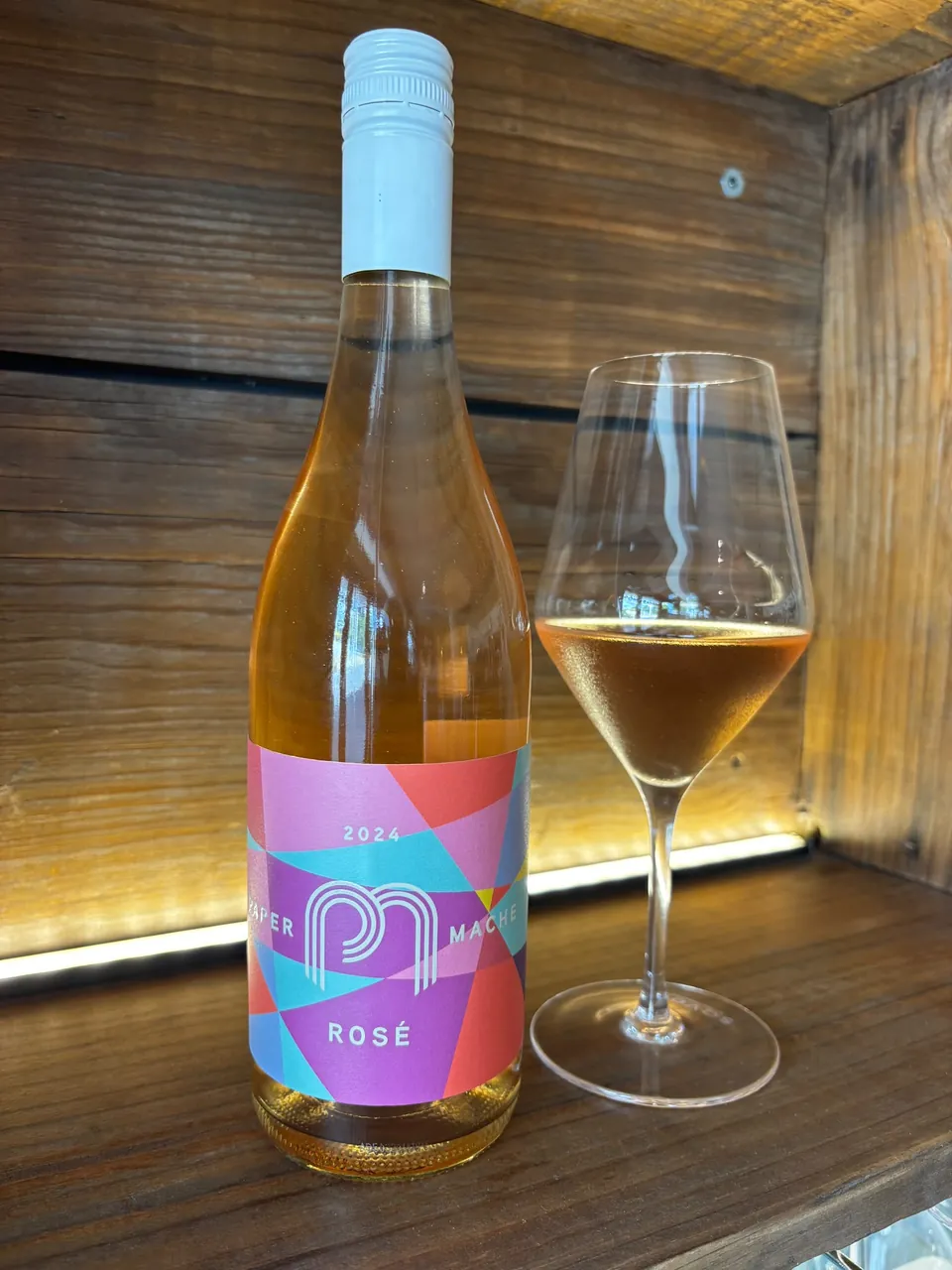 A bottle of Paper Mâché 2024 Rosé beside a glass of rosé