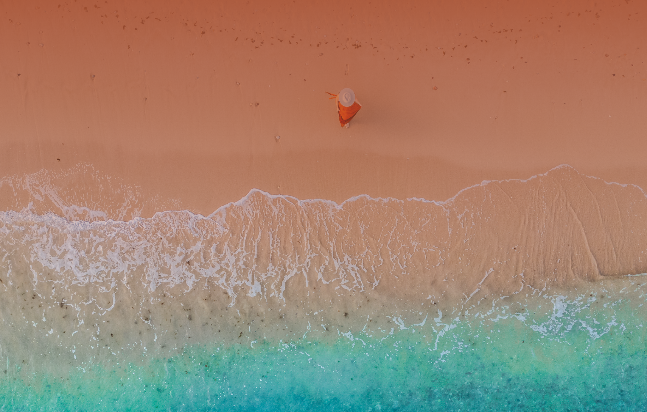 Aerial view of a golden shoreline meeting the turquoise ocean