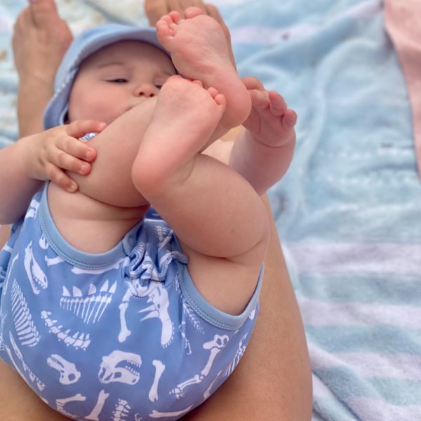 Baby holding their feet on a beach towel