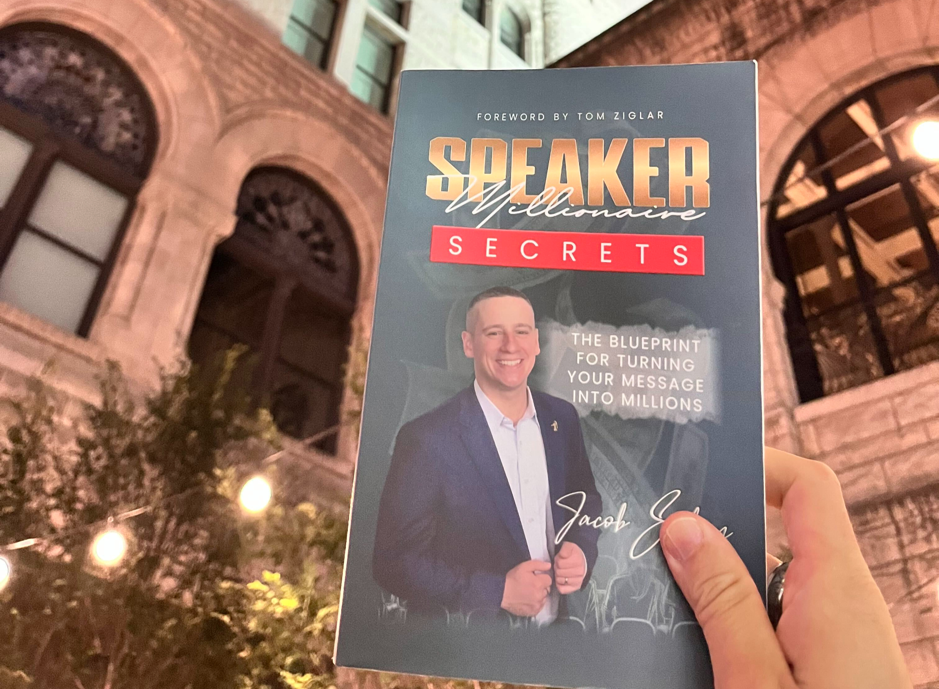 Speaker Millionaire Secrets held outside a city building