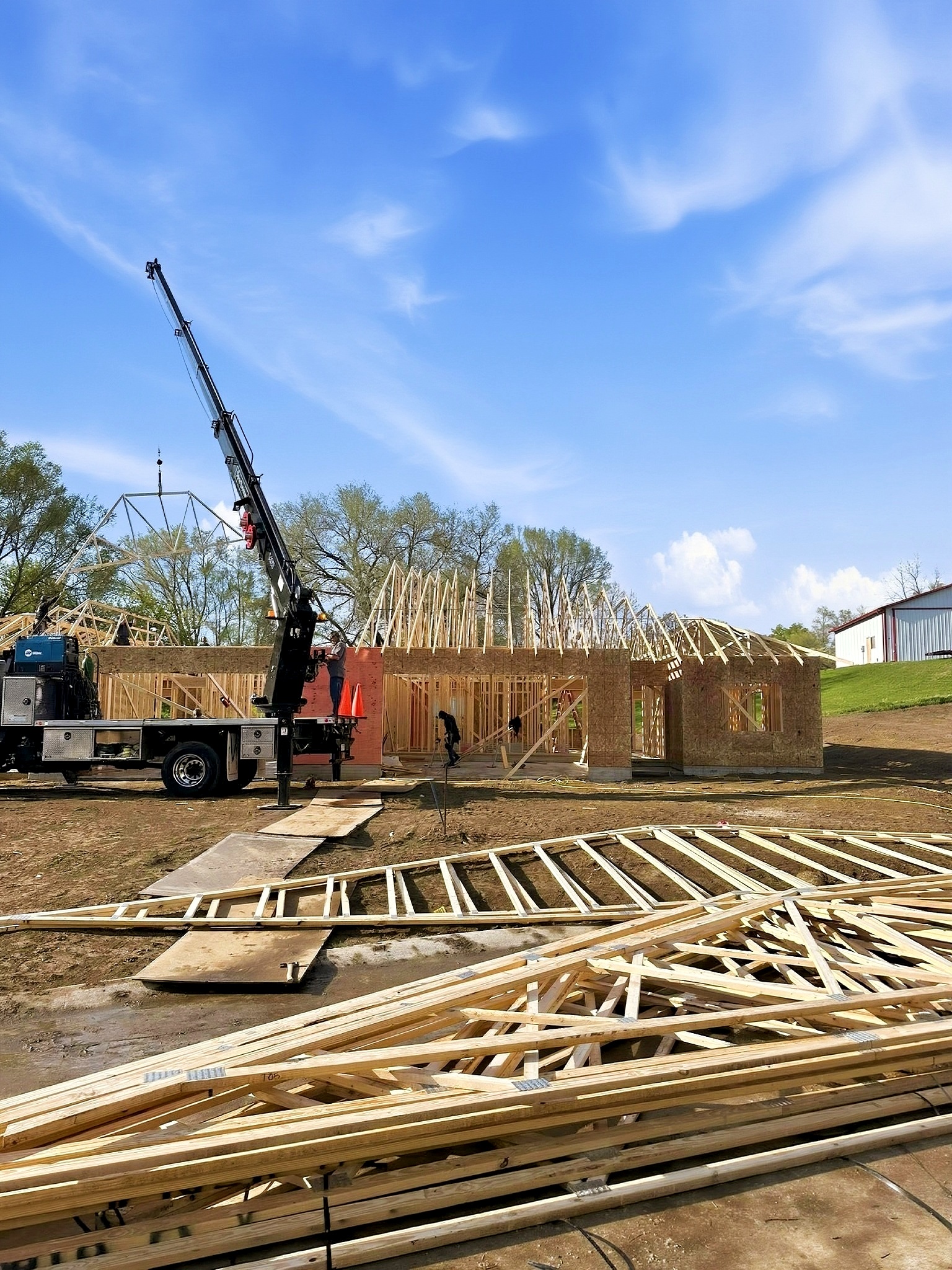 Crane lifting roof beams on a custom home build in Siouxland