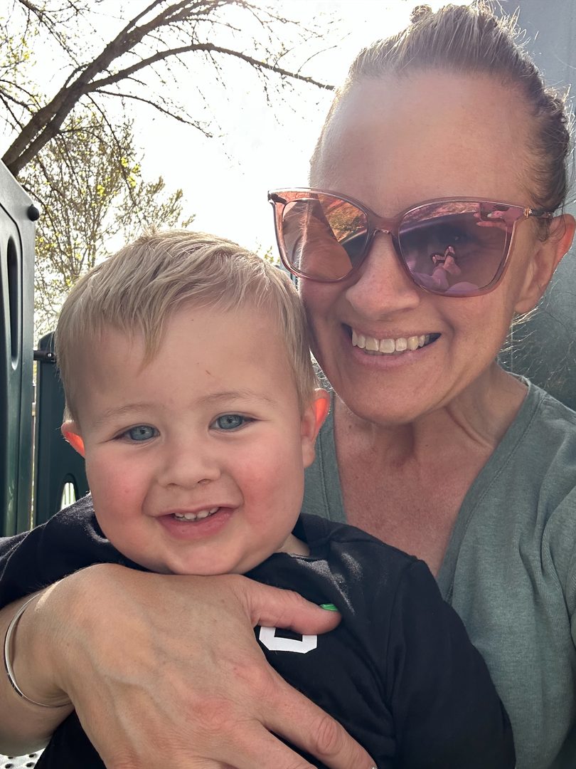 Calee, our owner, holding a happy toddler outdoors