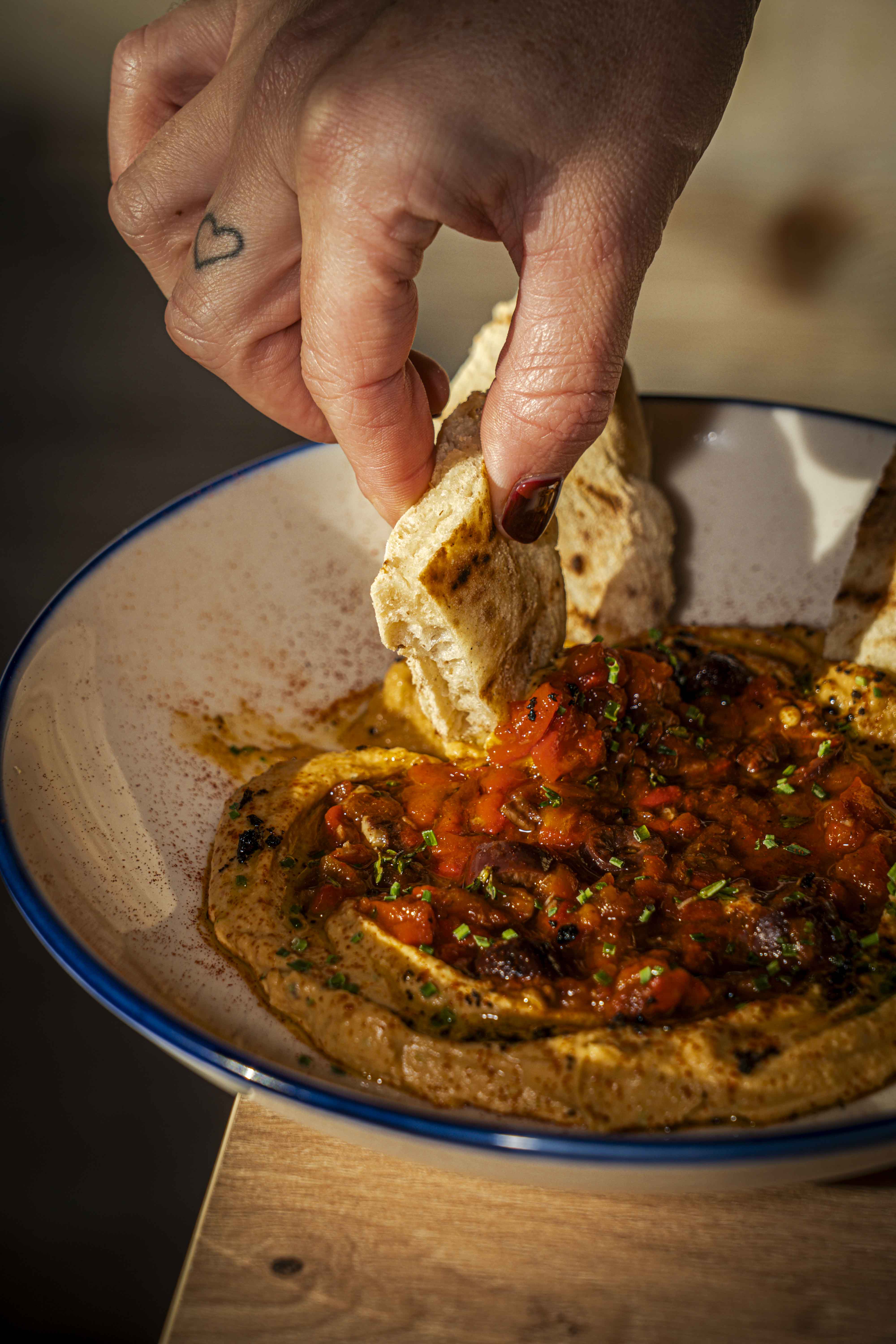 Mojar el pan en el hummus a la brasa
