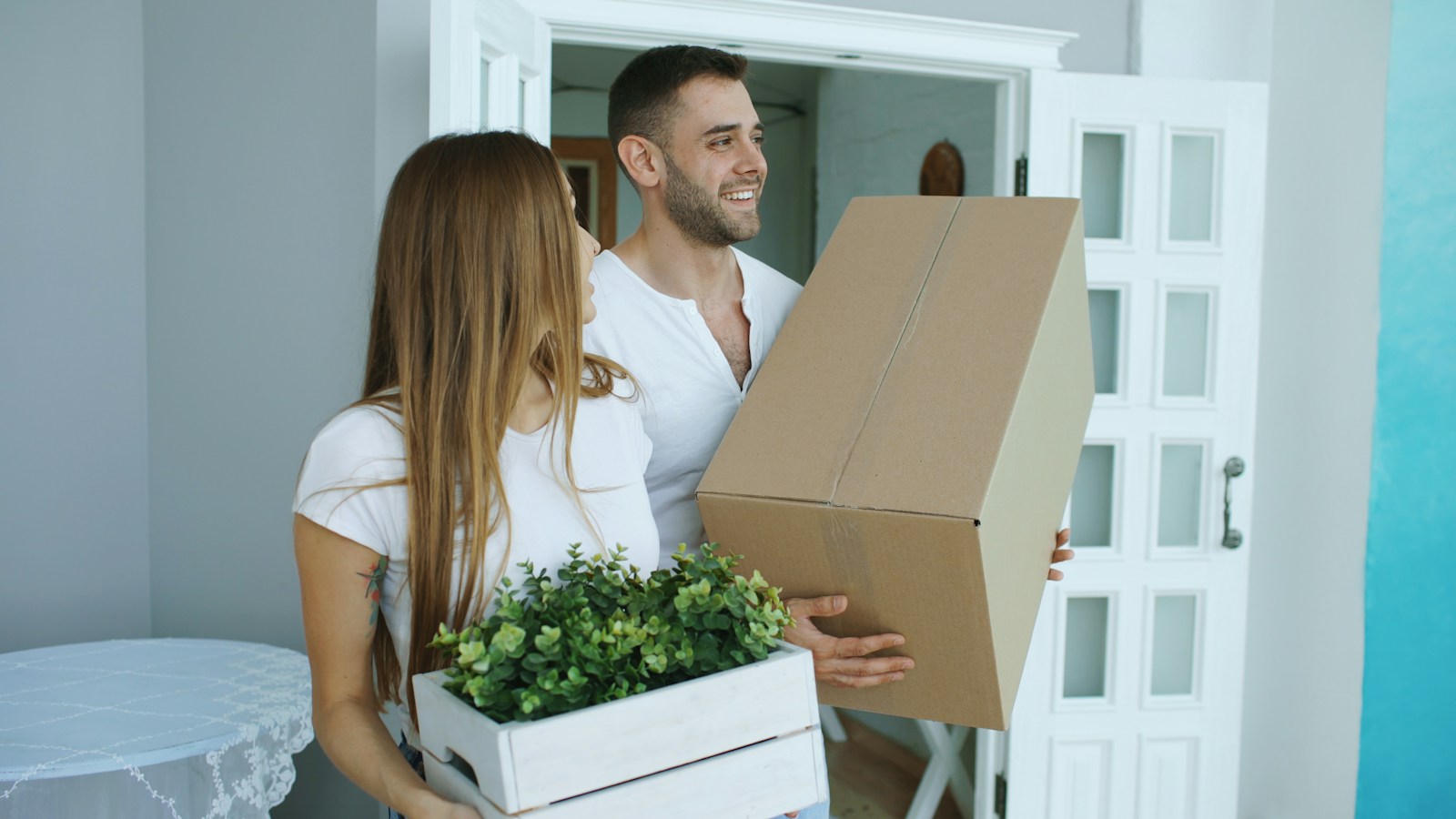 Couple carrying moving boxes into their home