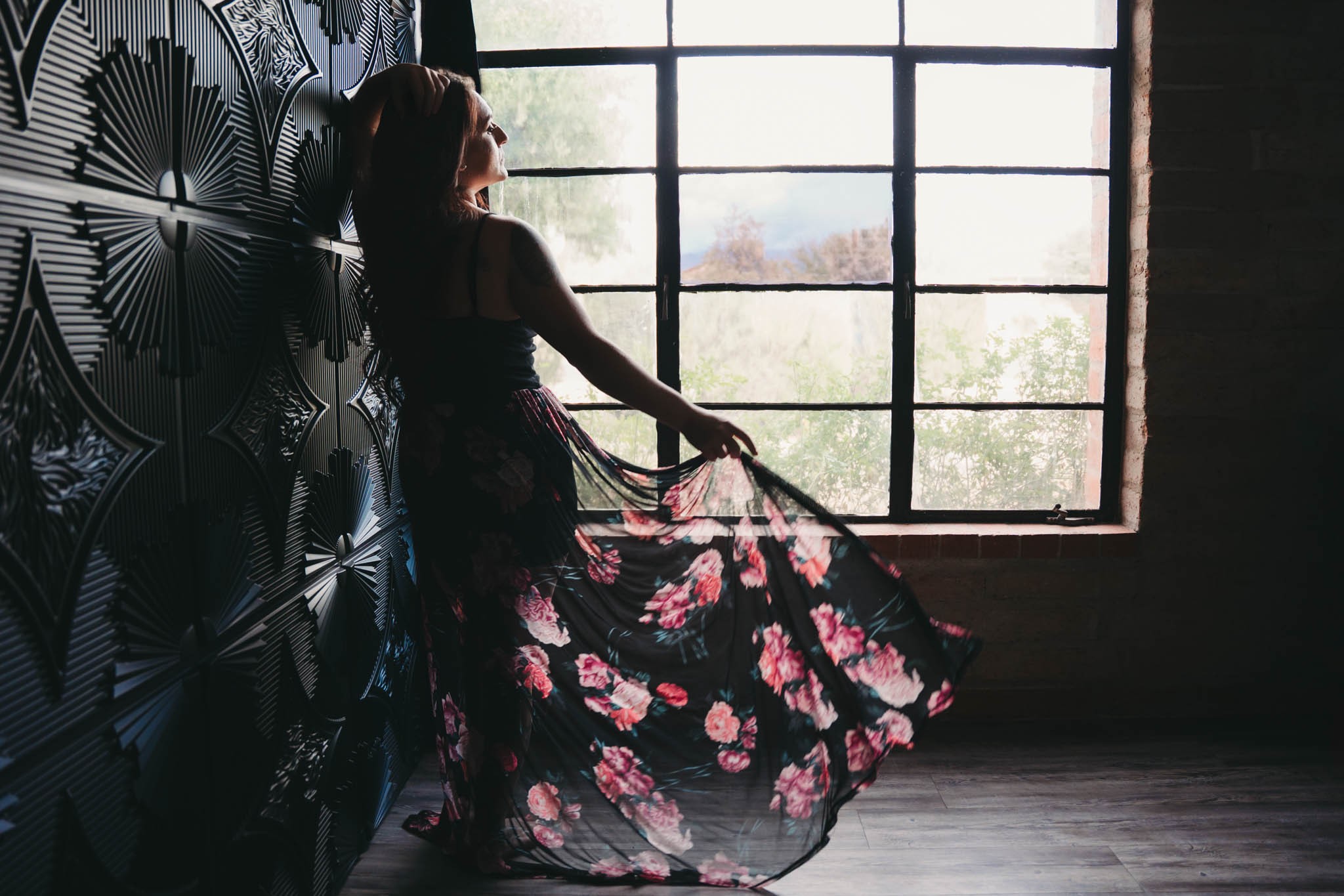 Woman in a flowing floral skirt standing by a window during a boudoir empowerment photography session | Jessica Korff Studios in Tucson, Arizona