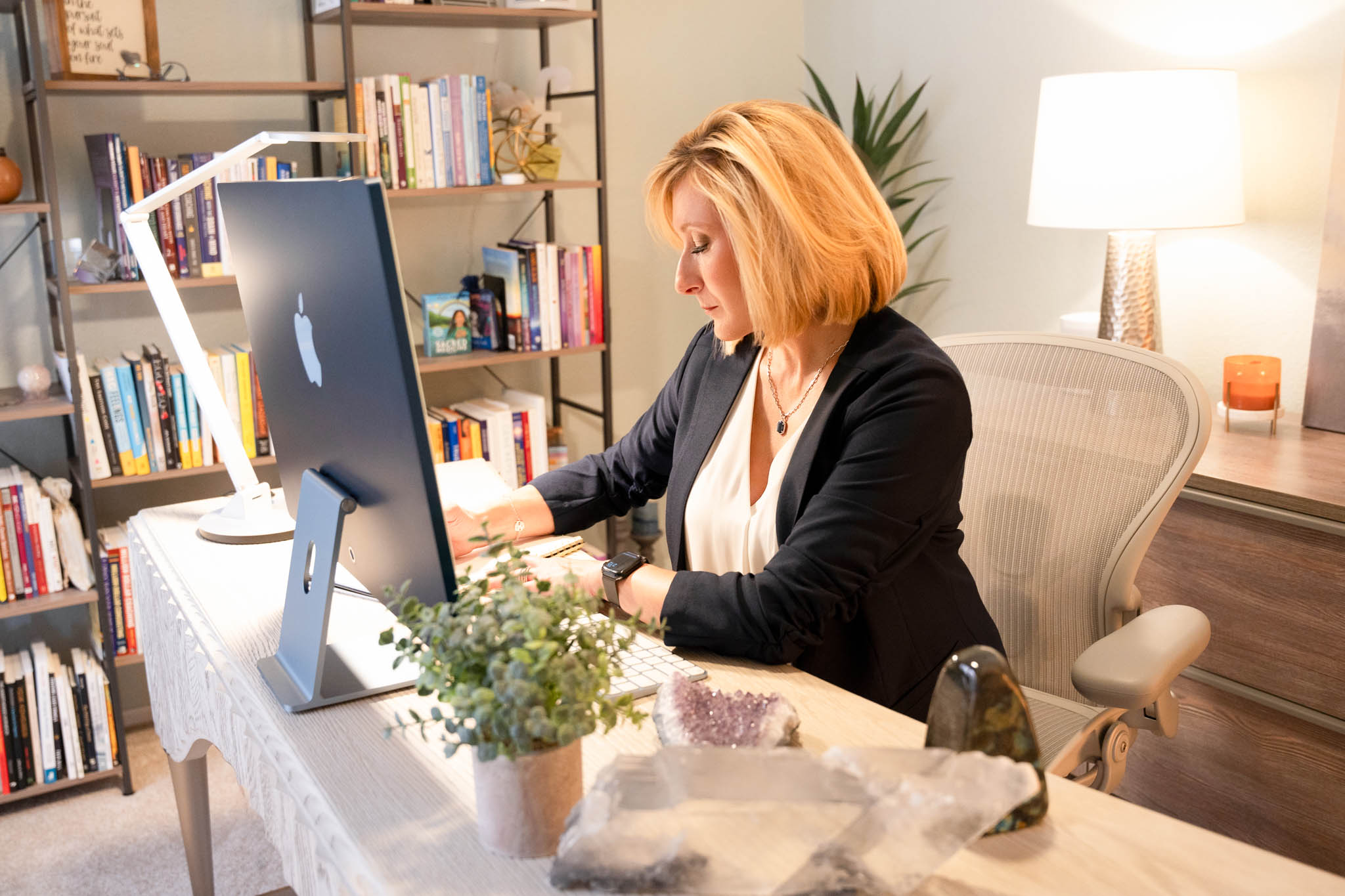 Female entrepreneur working at desk with books and computer in lifestyle branding office setting | Jessica Korff Studios Tucson, AZ