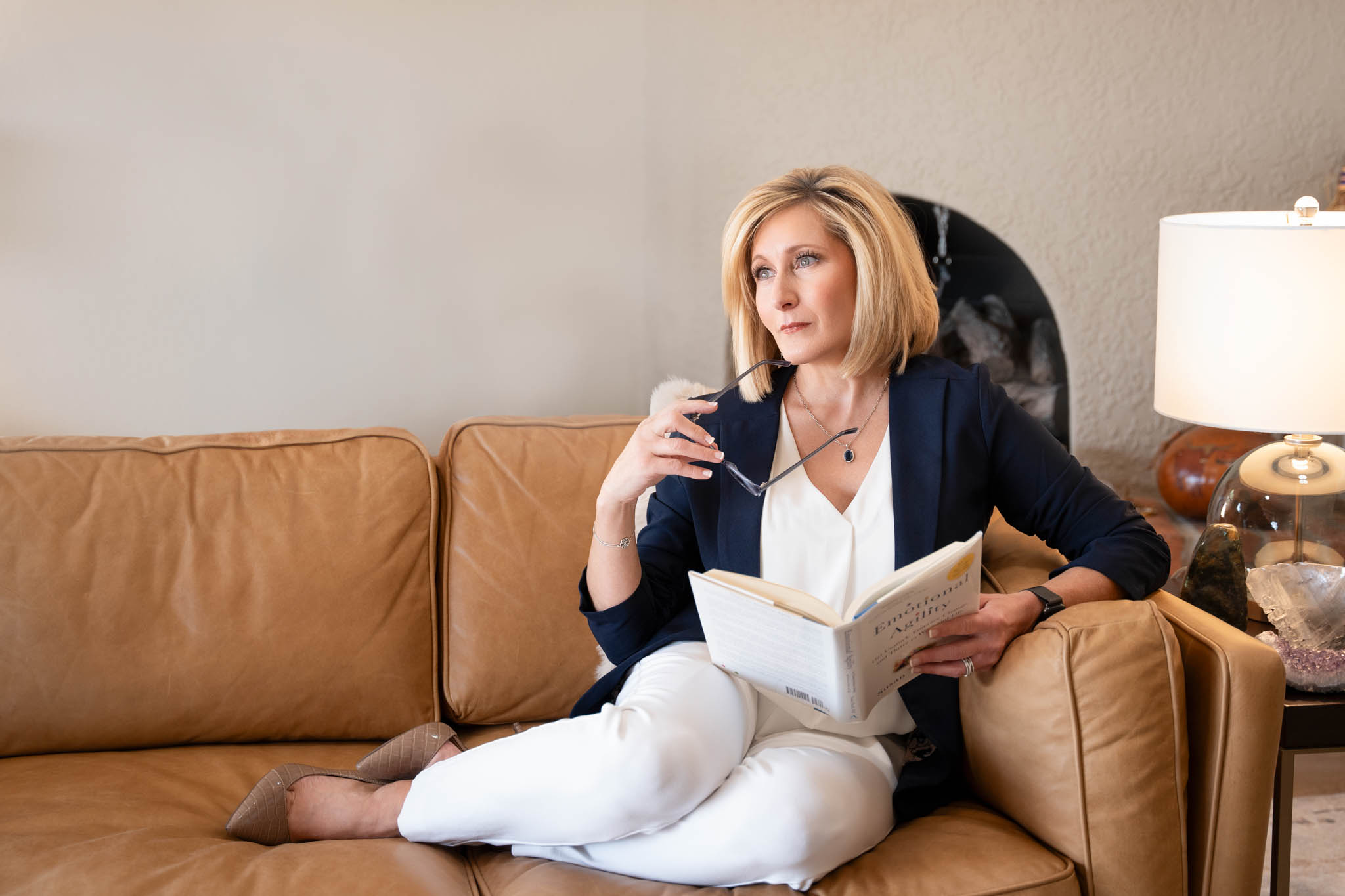 Personal branding image of woman reading book on couch in home office, thoughtful entrepreneur lifestyle | Jessica Korff Studios Tucson, AZ