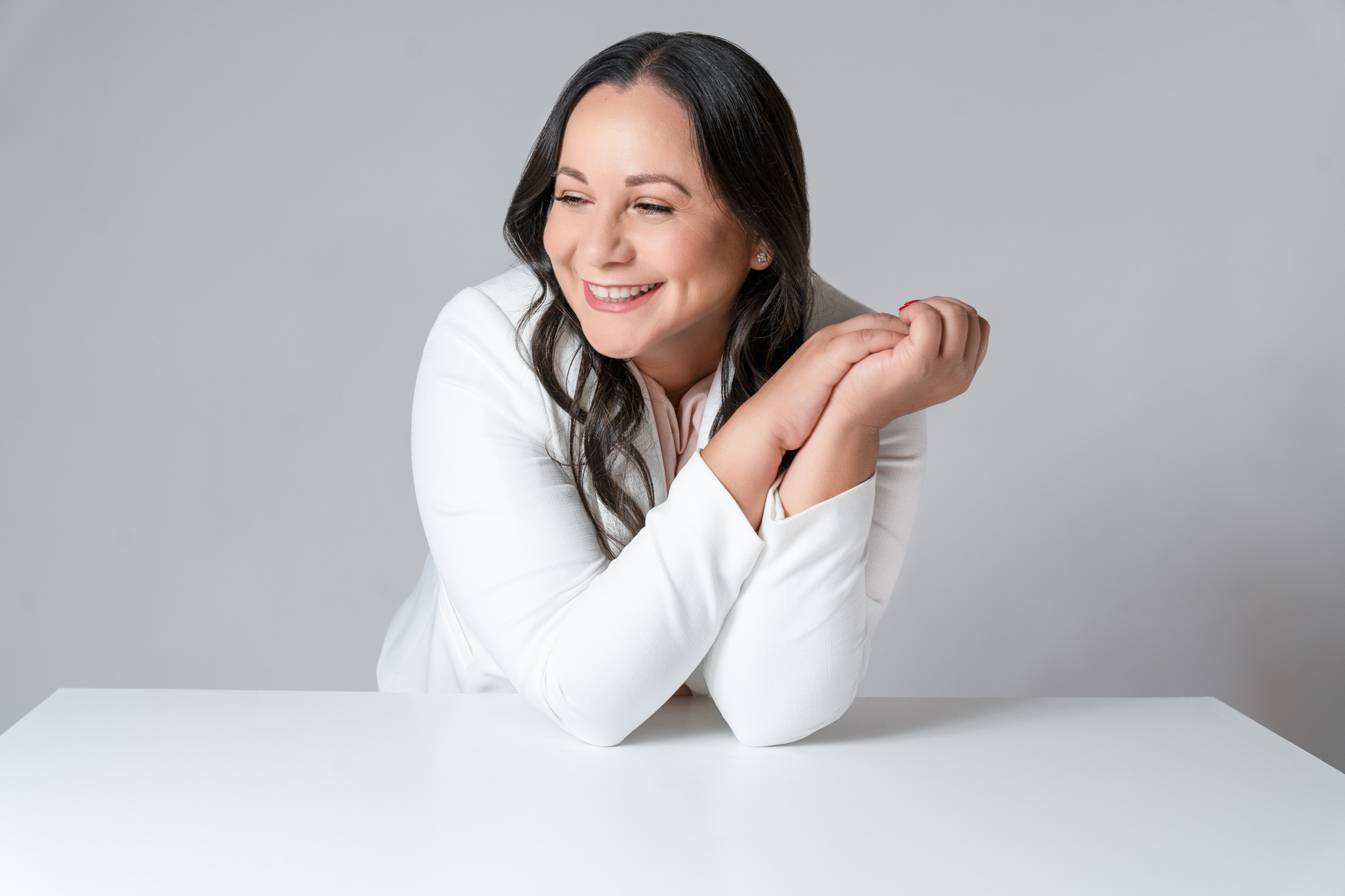 Female entrepreneur sitting at desk with hands clasped and smile on face in lifestyle branding office setting | Jessica Korff Studios Tucson, AZ