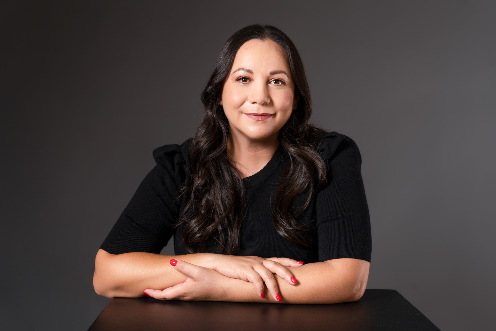 Woman sitting at table with dark background during branding session | Jessica Korff Studios Tucson, AZ