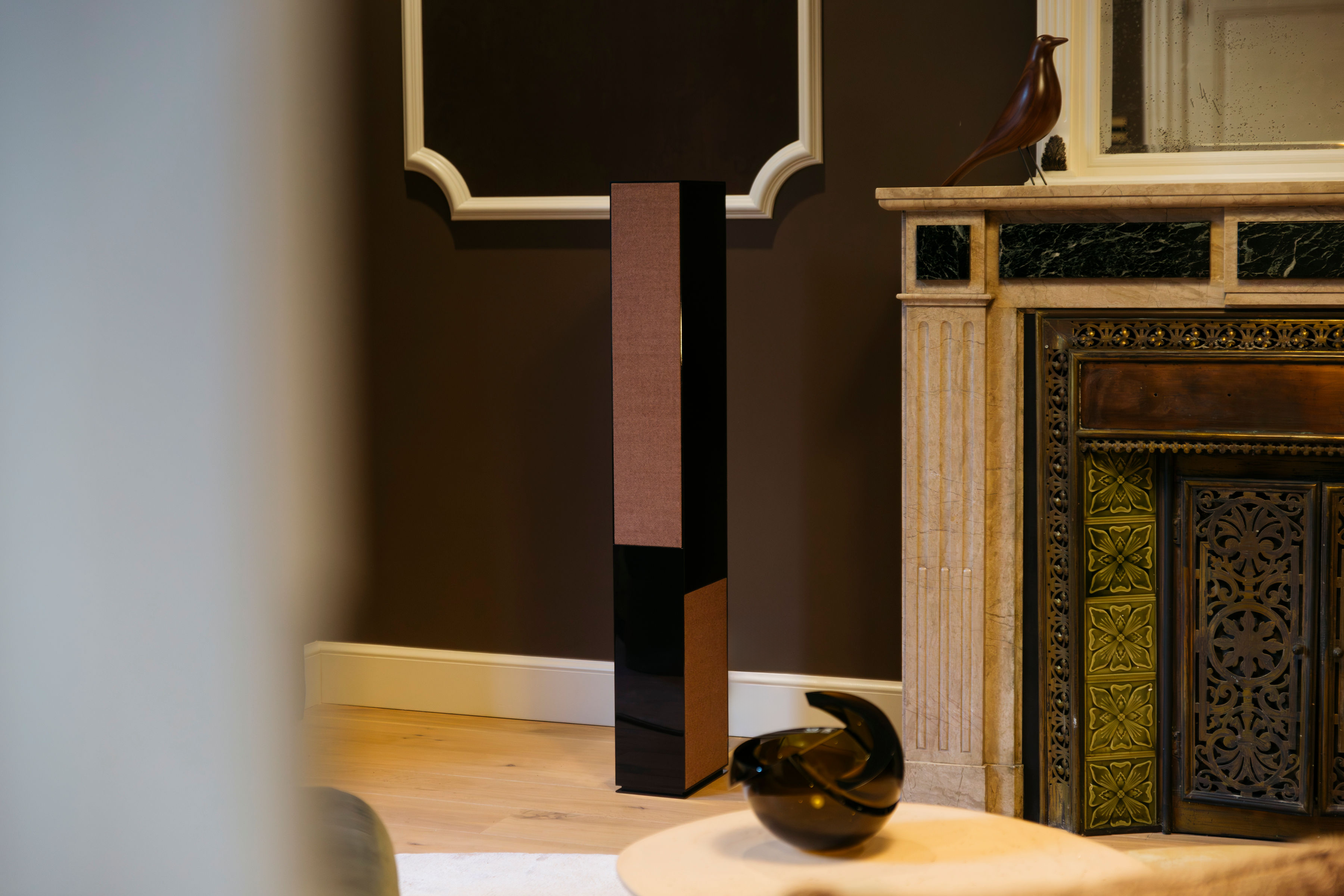 Enceinte colonne Basalte Aalto F5 finition tissu rouille à côté d'une cheminée — audio haut de gamme intégré Vestalia PACA