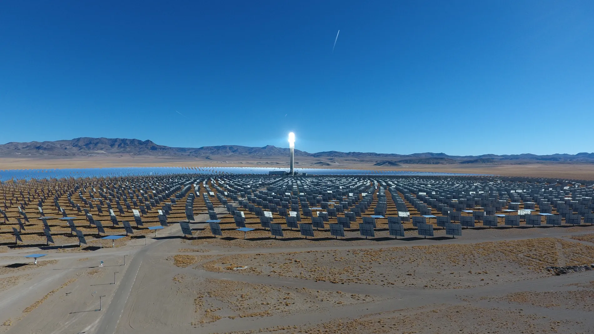 The solar field stretching to the mountains on the horizon, with the tower at its center.