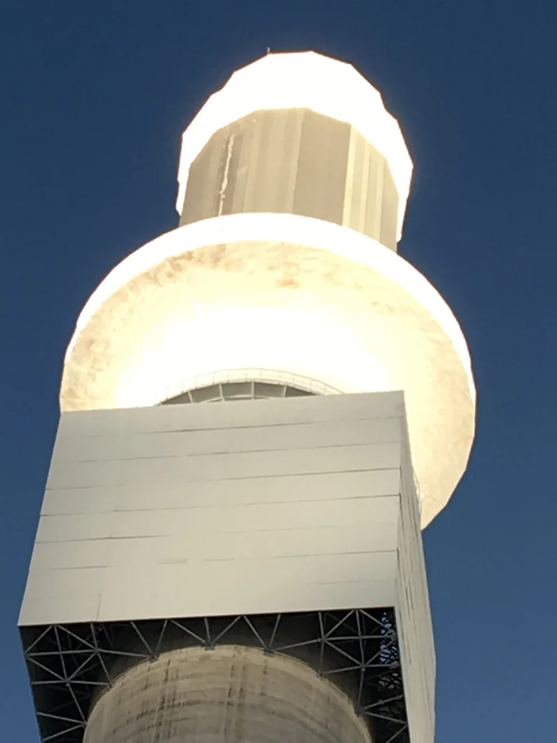 The receiver at the top of the tower, glowing white with concentrated sunlight.