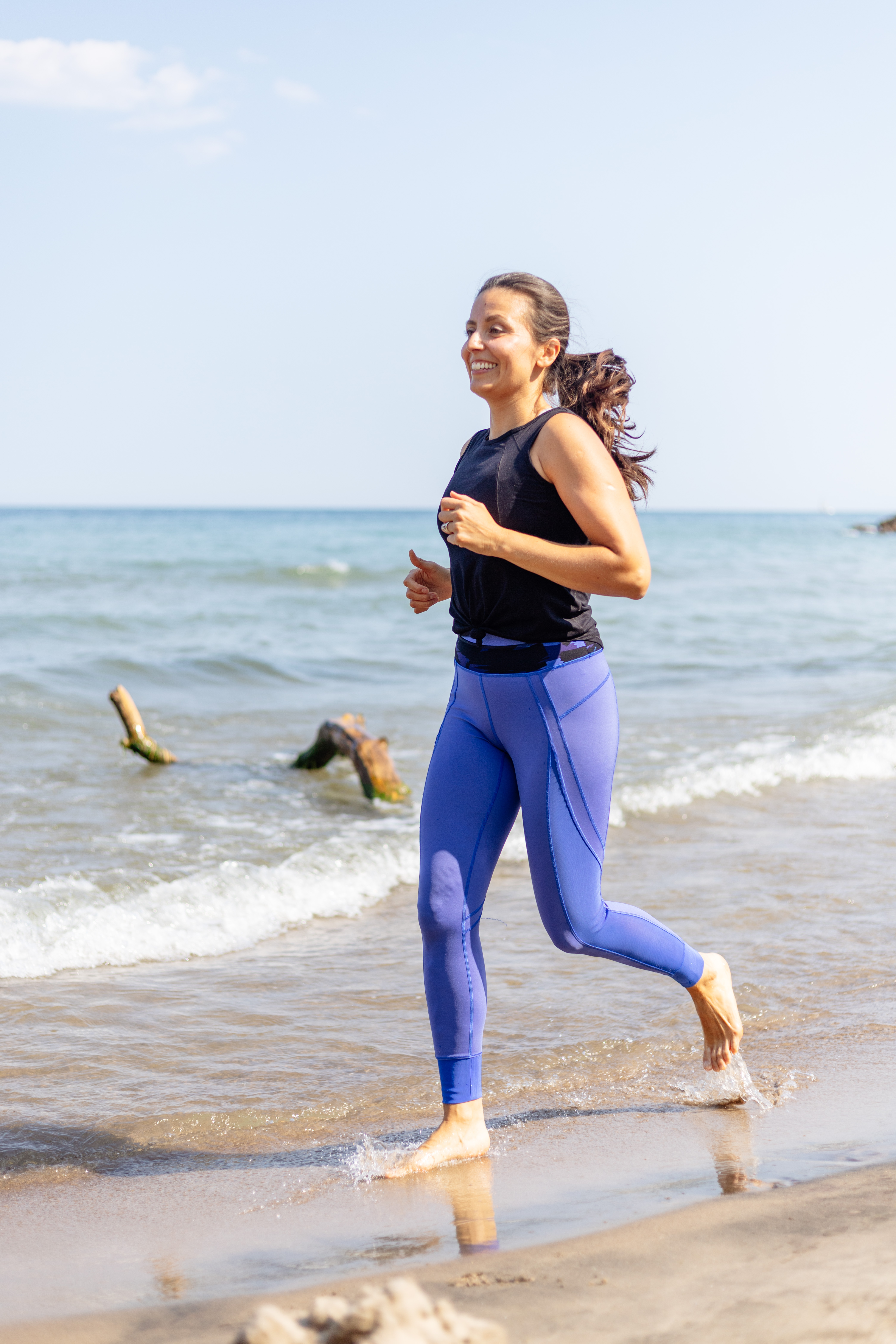 Daniela running along the beach shoreline with vitality and joy