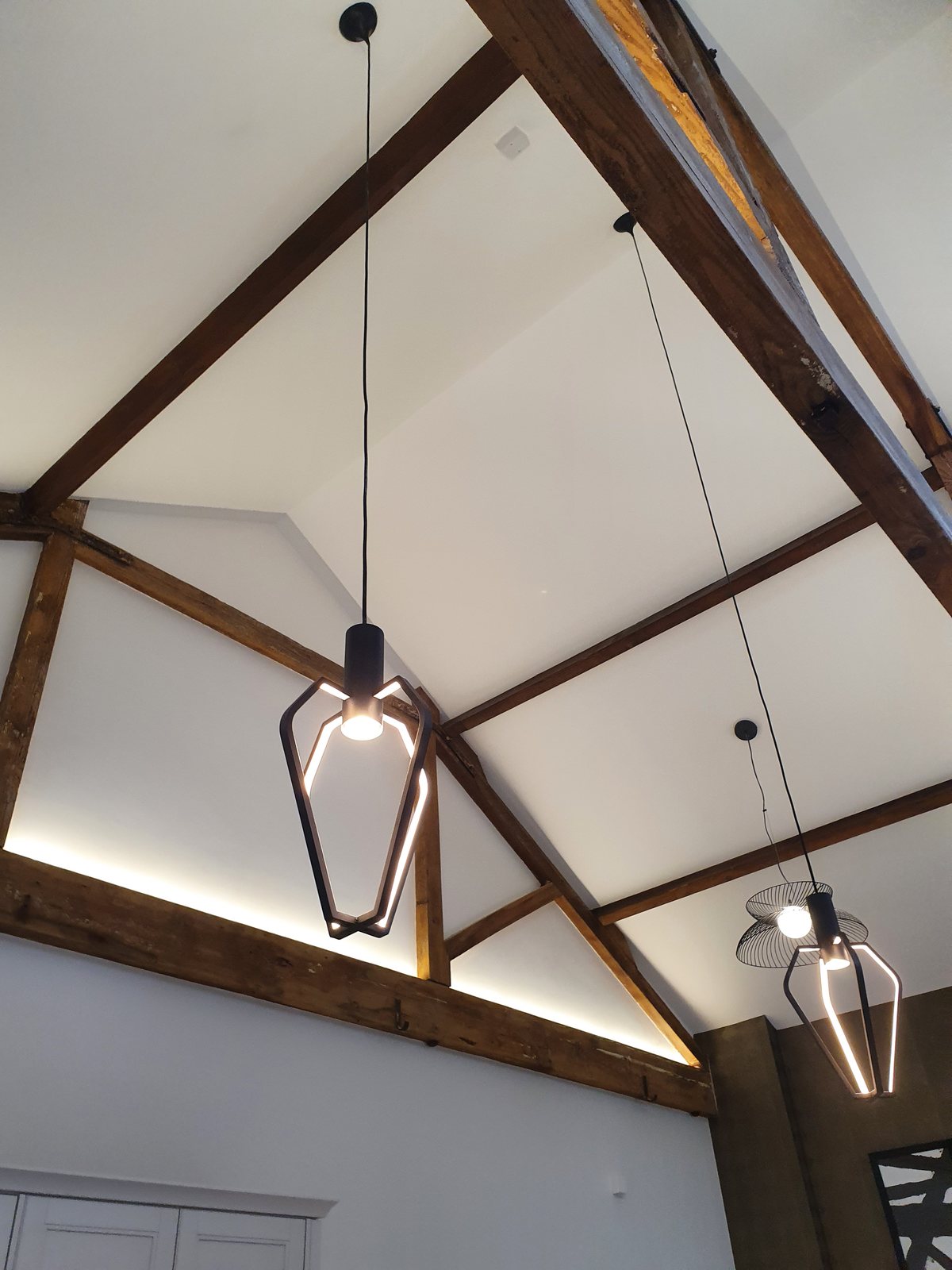Pendant light fitting between exposed timber roof trusses by Cord Electrical