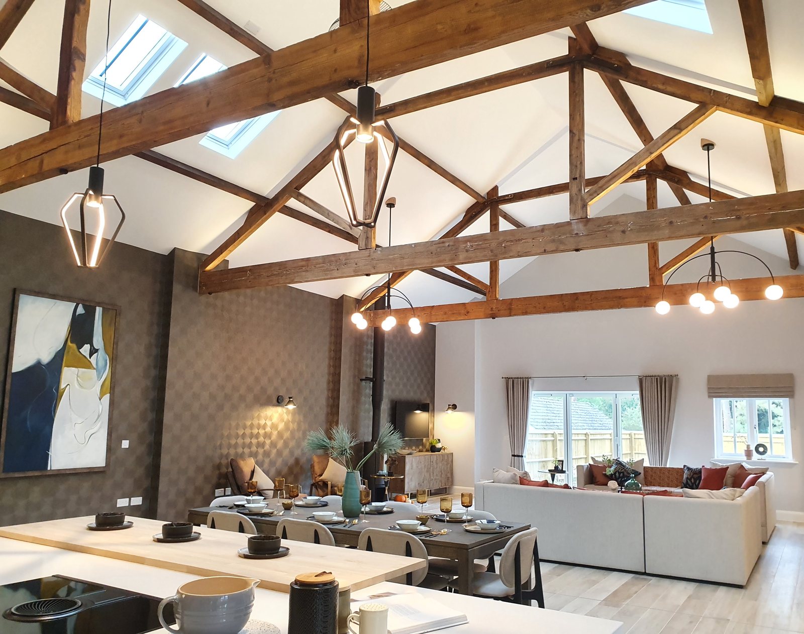Pendant lighting installed under exposed oak trusses in a barn conversion