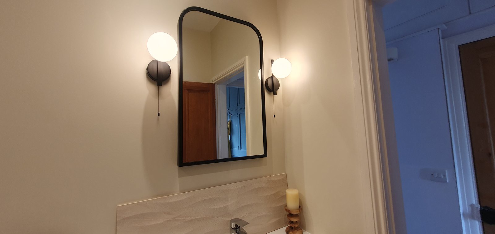 Two bathroom wall lights fitted either side of a mirror by Cord Electrical
