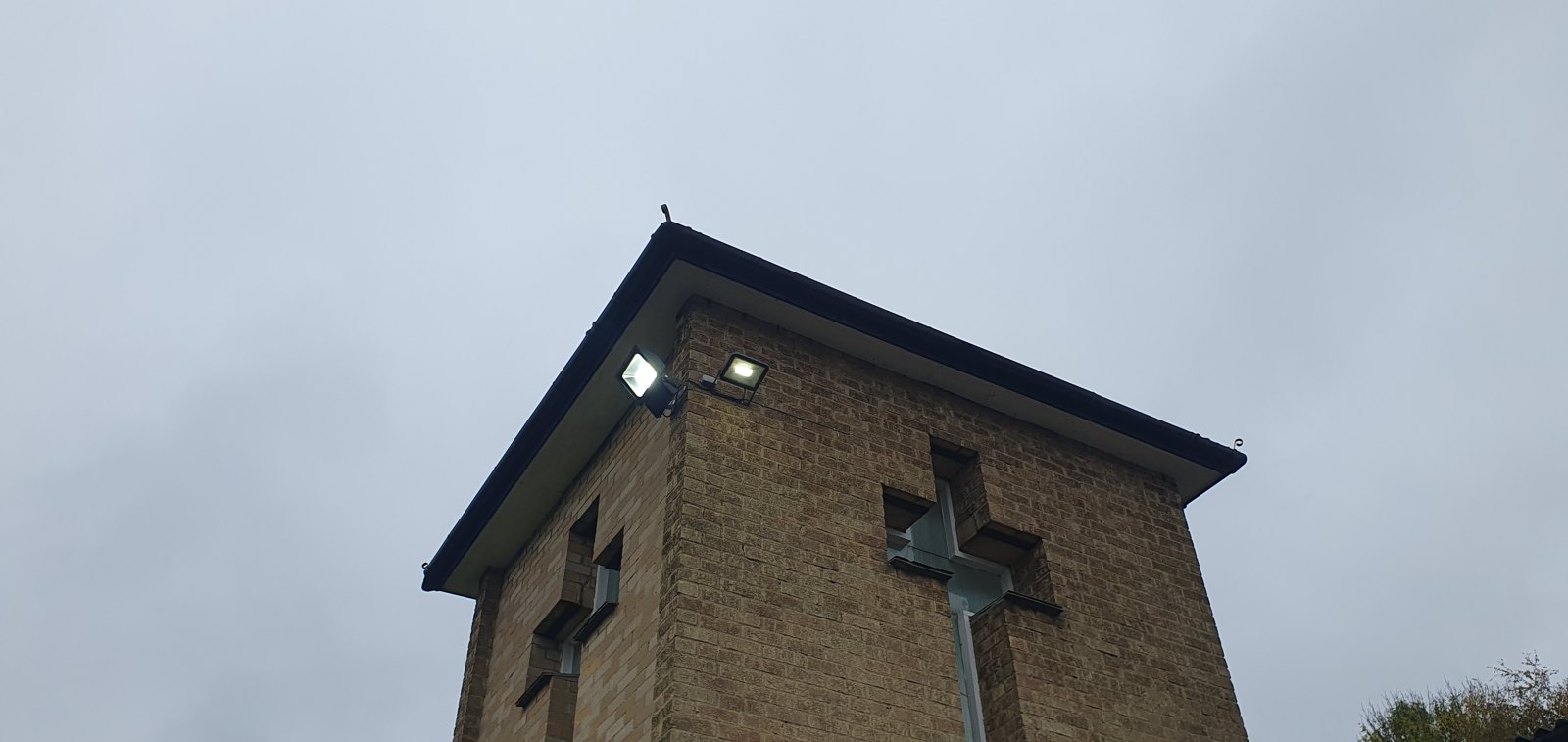 Floodlights mounted high on a church exterior to light the car park