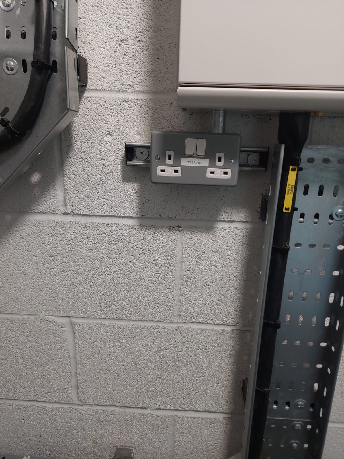 Socket outlet on blockwork beside a steel cable tray