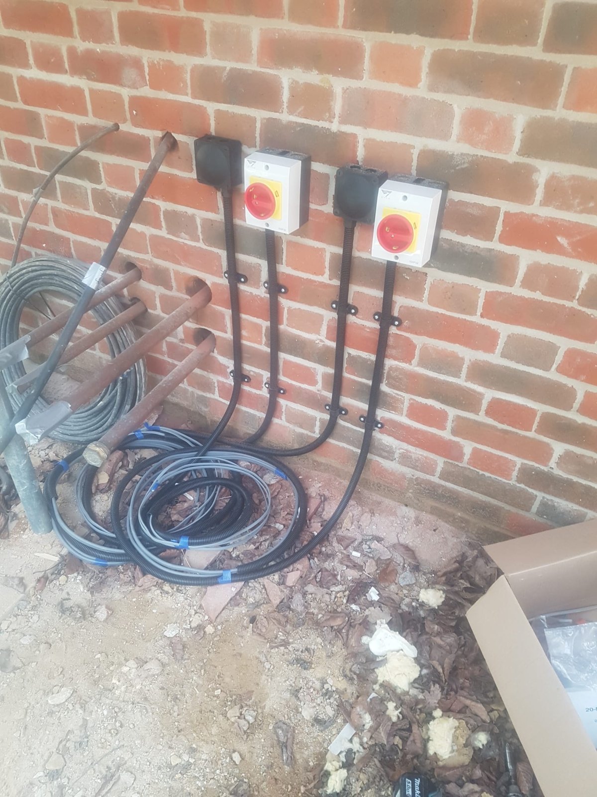 Two rotary isolators on a brick wall with coiled armoured cable