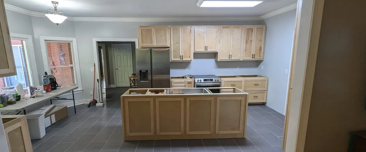 A kitchen undergoing renovation with custom cabinetry and modern finishes, including a kitchen island.
