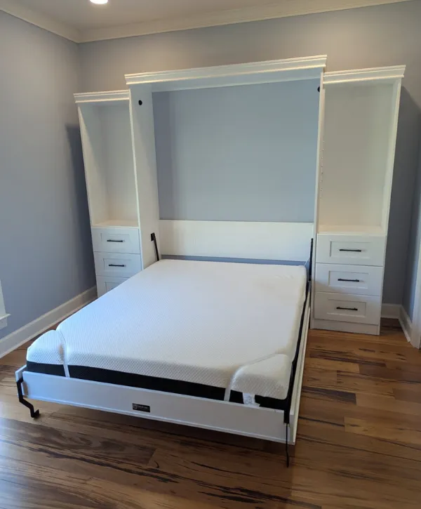 White Murphy bed with built-in side drawers and shelves in a light blue bedroom